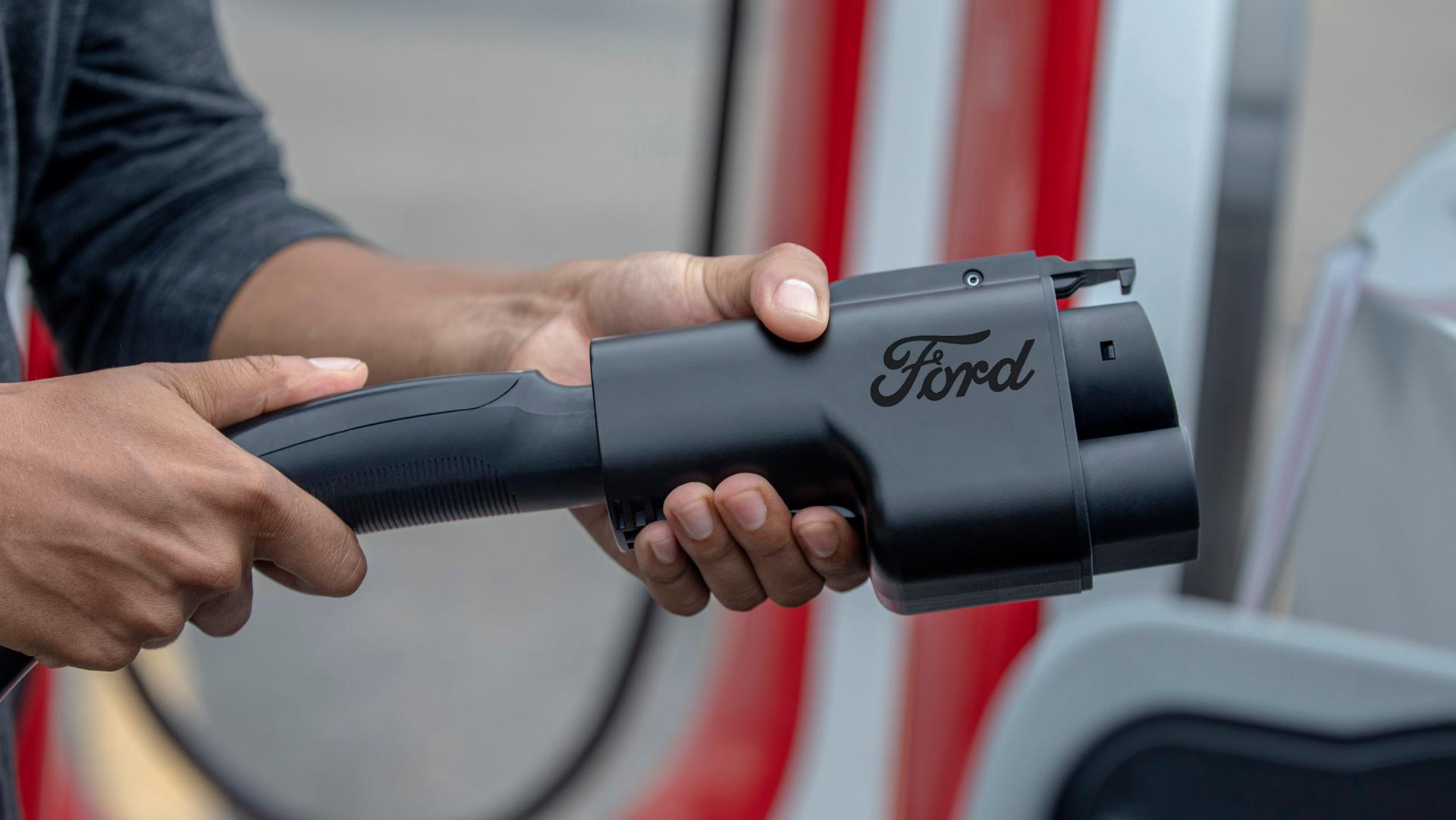 Person using the NACS charging adapter for a Tesla Supercharger