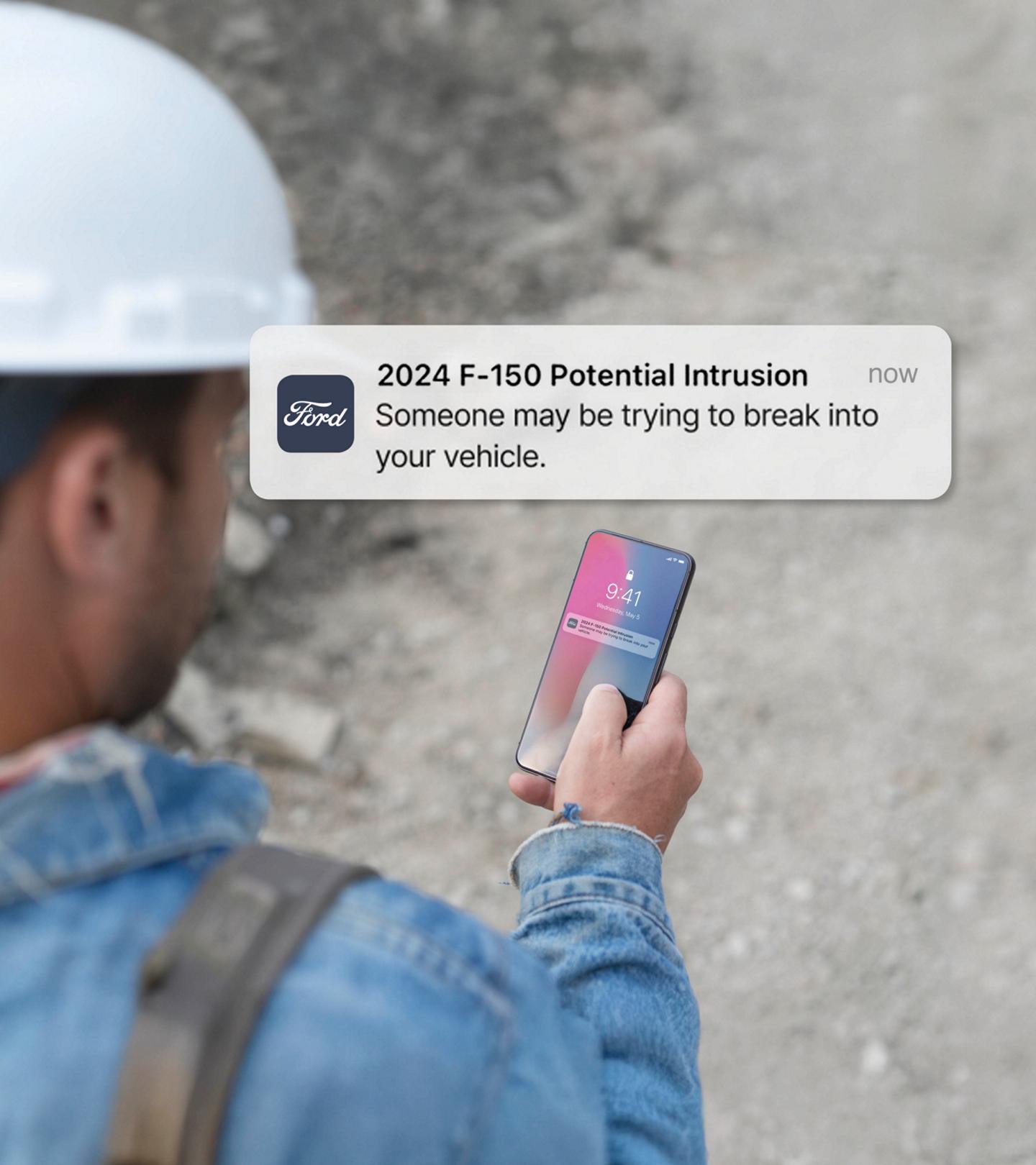 Person holding a smartphone displaying a notification. Overlay of text that reads: Potential intrusion! Someone may be trying to break into your vehicle.