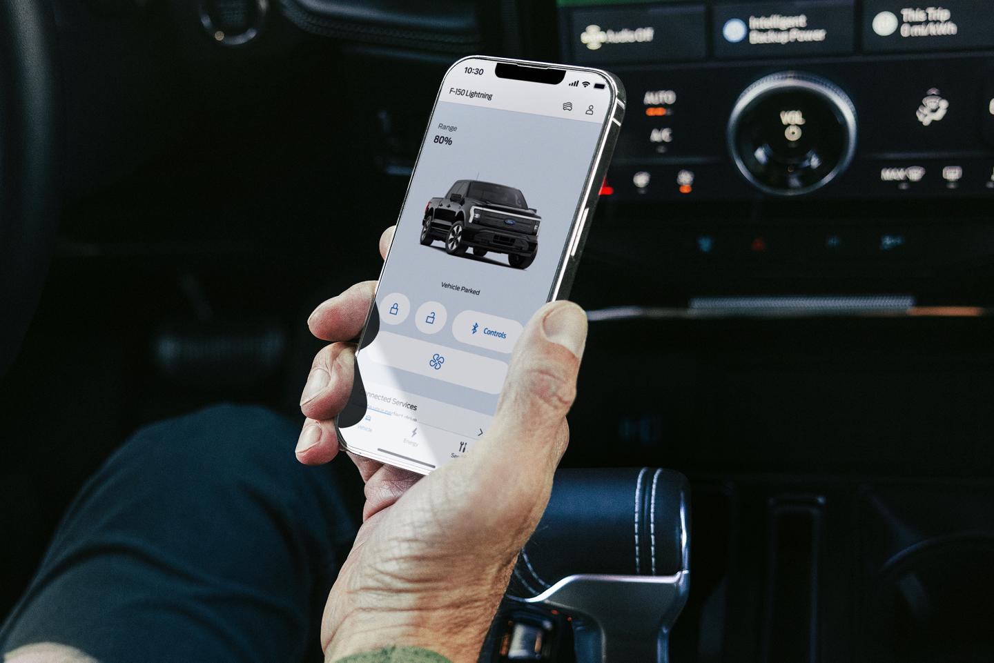Person holding a smartphone open to the Ford app.