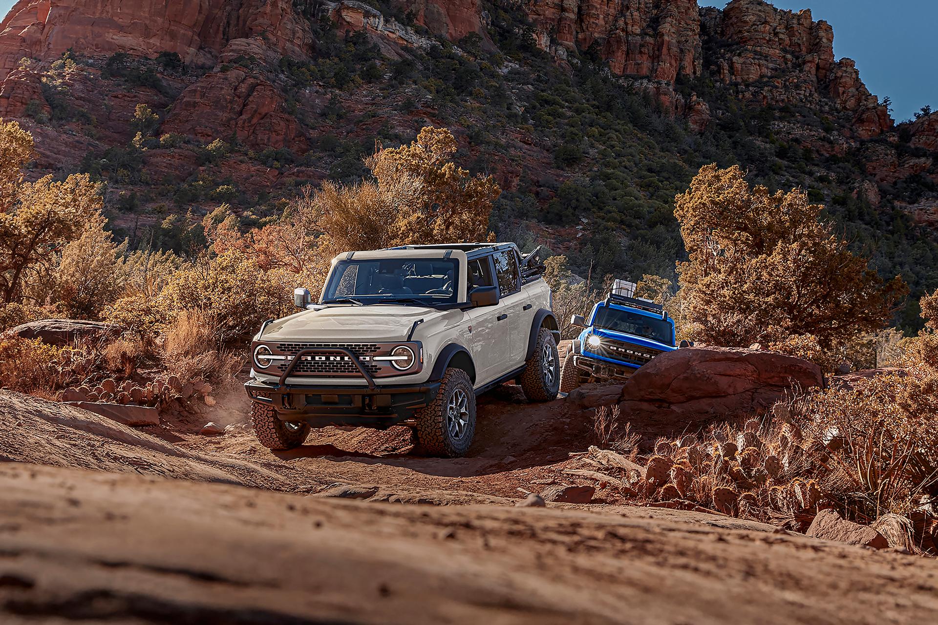 Two 2026 Ford Bronco® SUVs being driven on a scrubby dirt trail