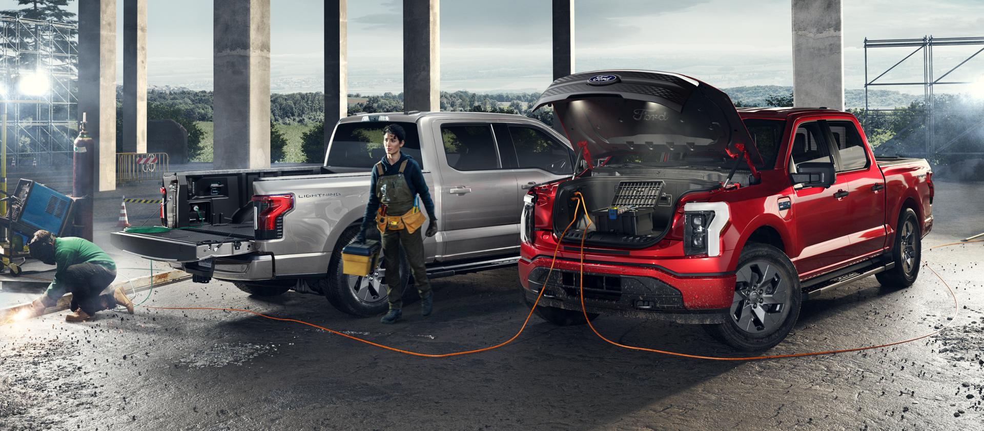 Two F-150 Lightning trucks parked at a construction site with power tools and equipment plugged into them.