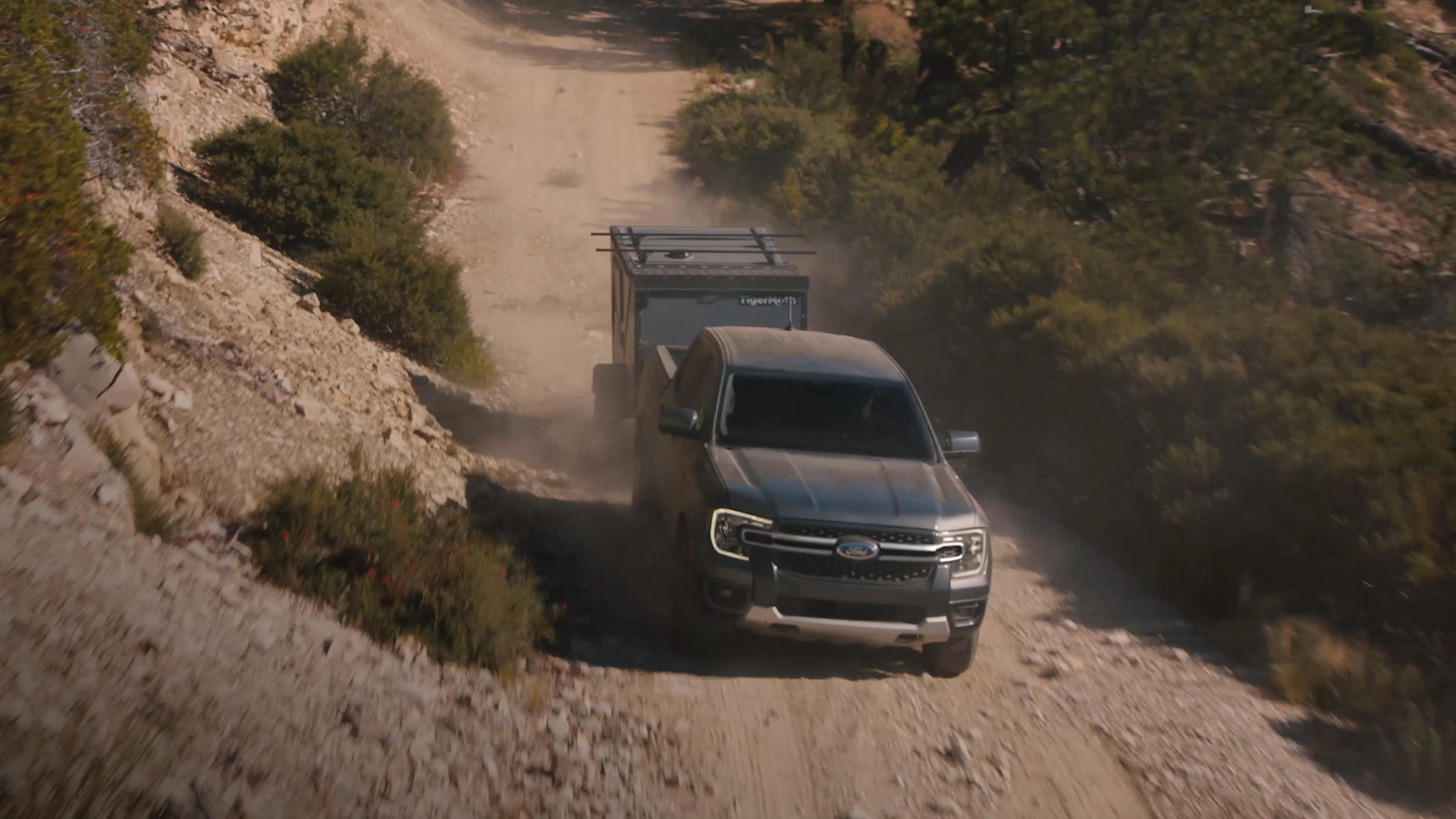 2026 Ford Ranger® truck towing a trailer on a dirt road in the mountains
