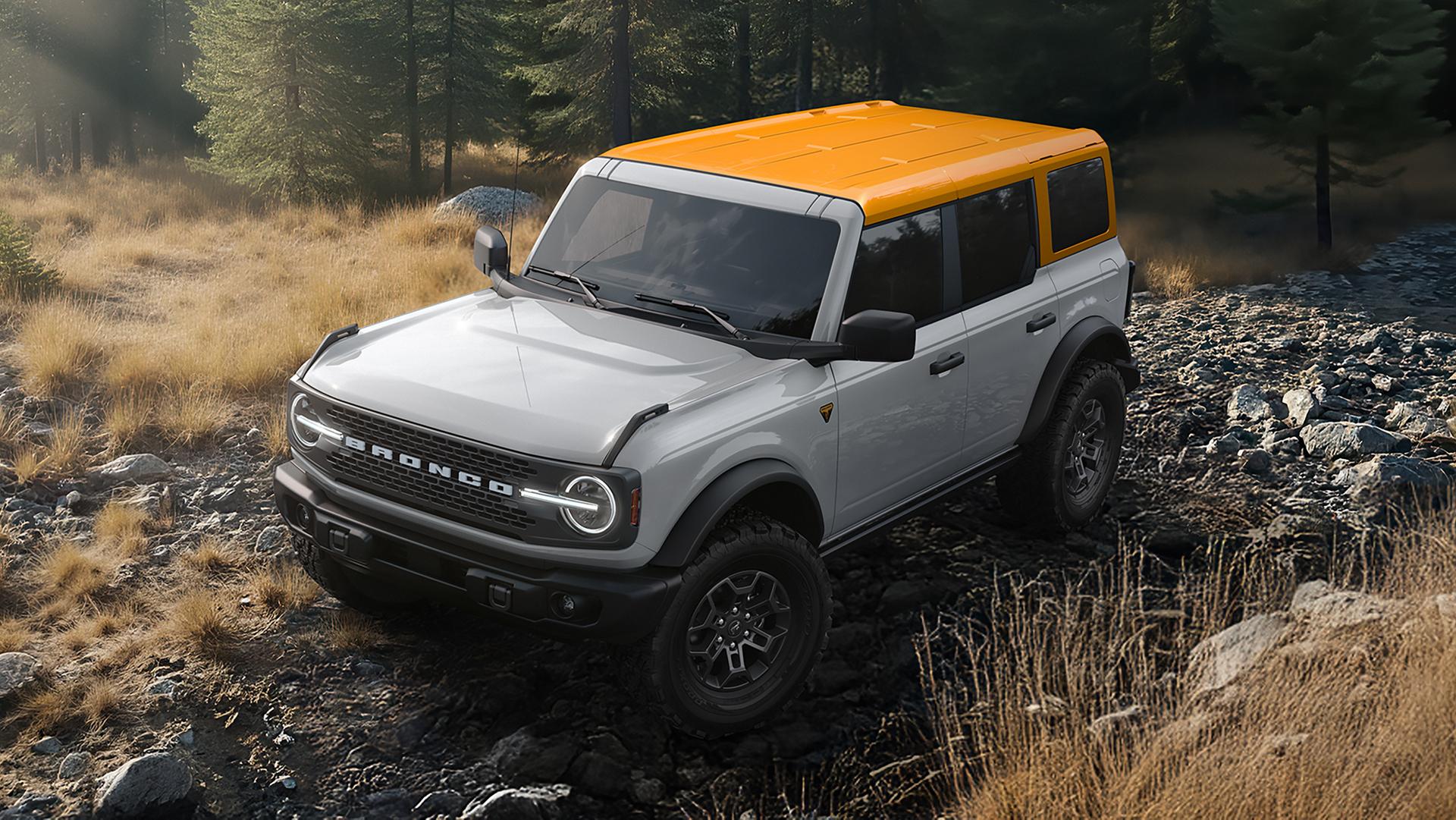 A 2026 Ford Bronco® SUV on a muddy path, with a light-coloured body and a orange roof