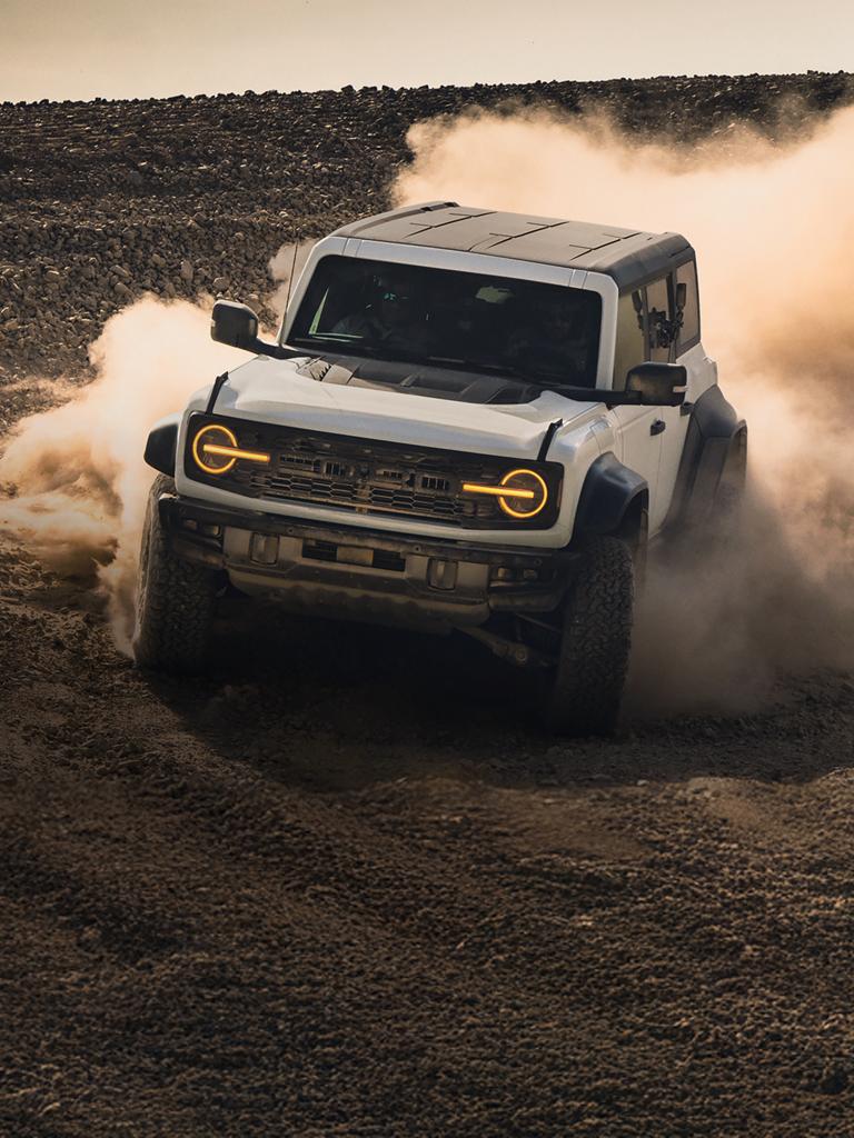 A 2026 Ford Bronco® SUV kicking up dust in a field