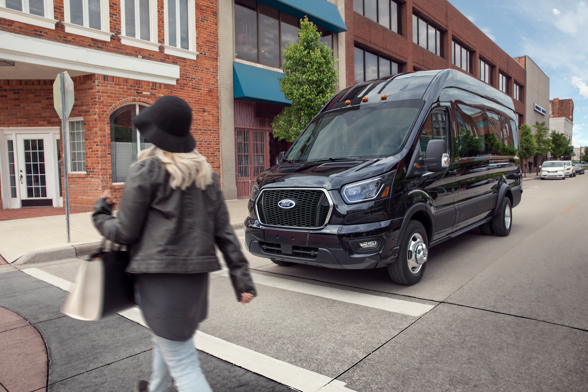 A 2026 Ford Transit® van stopped at a stop sign waiting for pedestrian to cross
