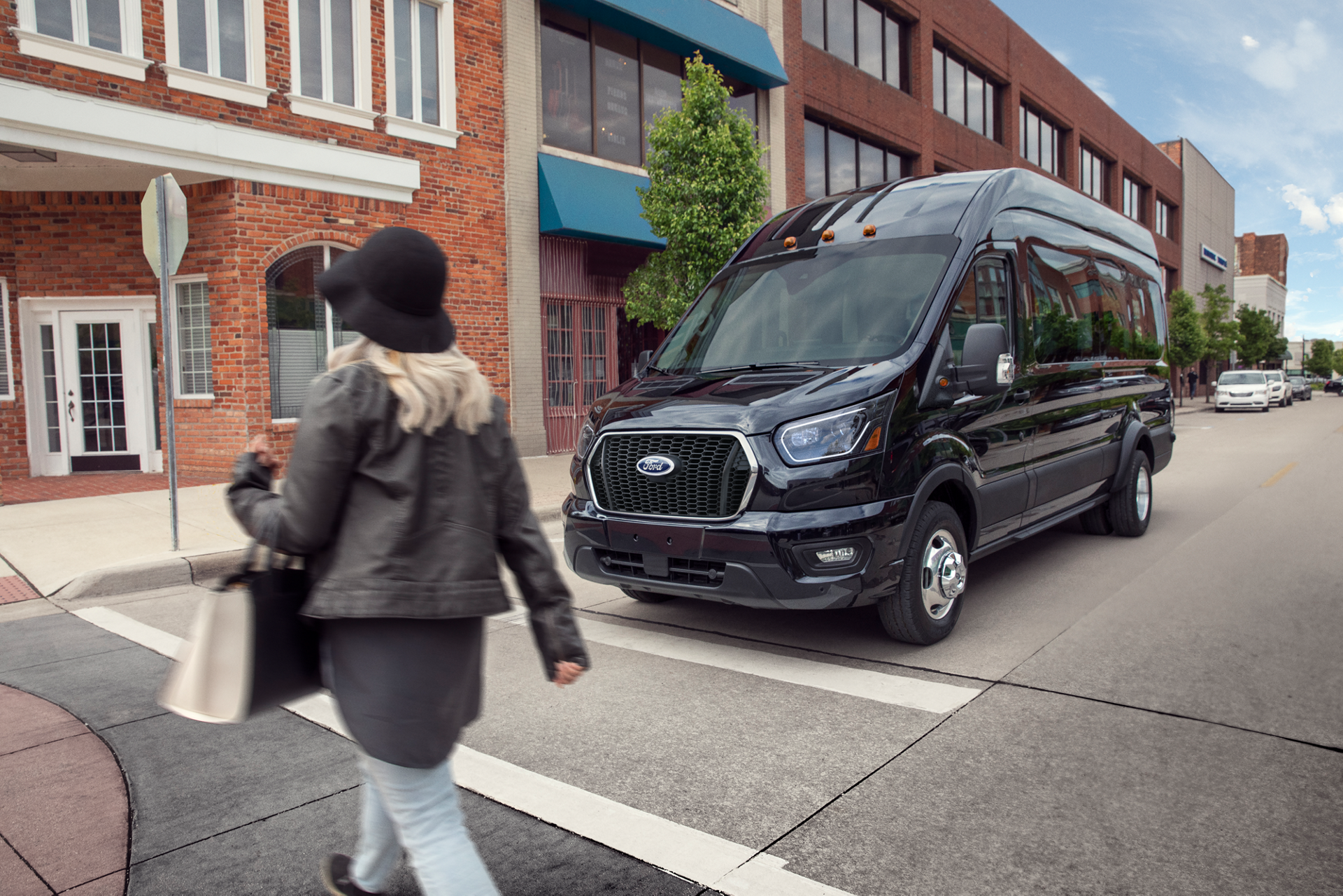 A 2026 Ford Transit® van stopped at a stop sign waiting for pedestrian to cross