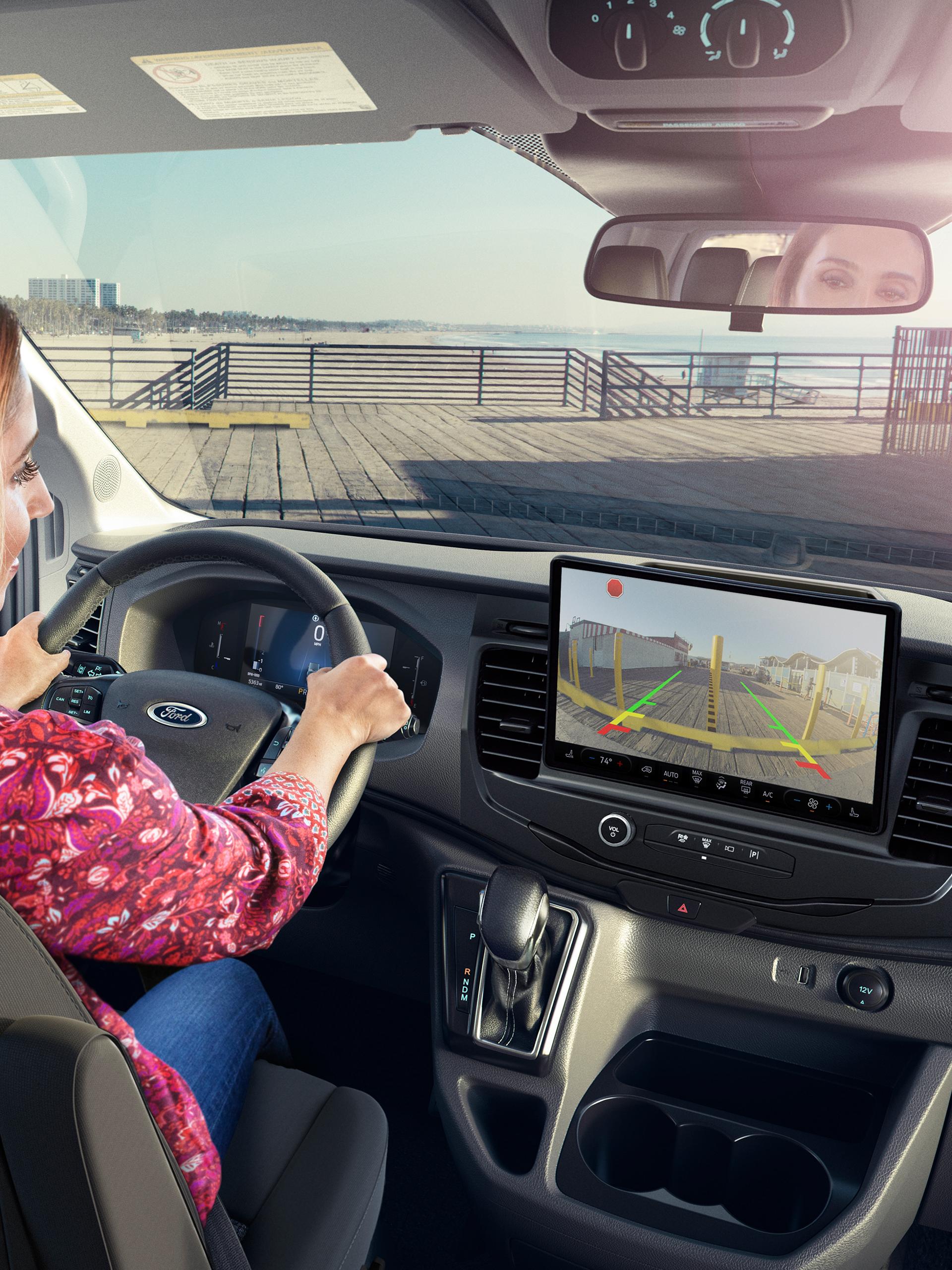 Woman in 2027 Ford Transit® Van using rearview camera display with parking sensors