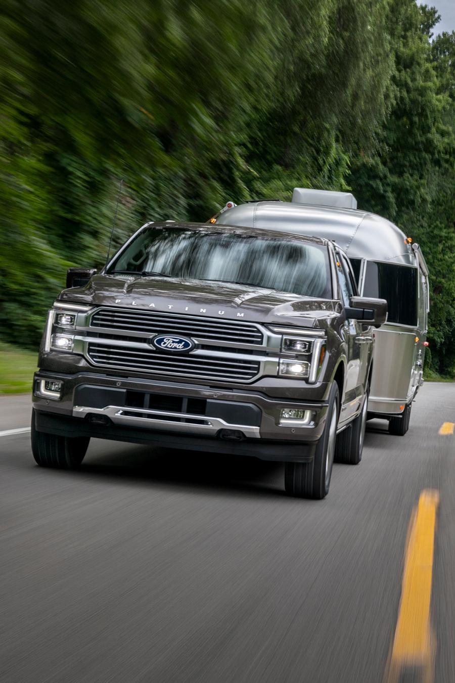 A 2025 F-150 with hitched RV trailer driving on a highway.