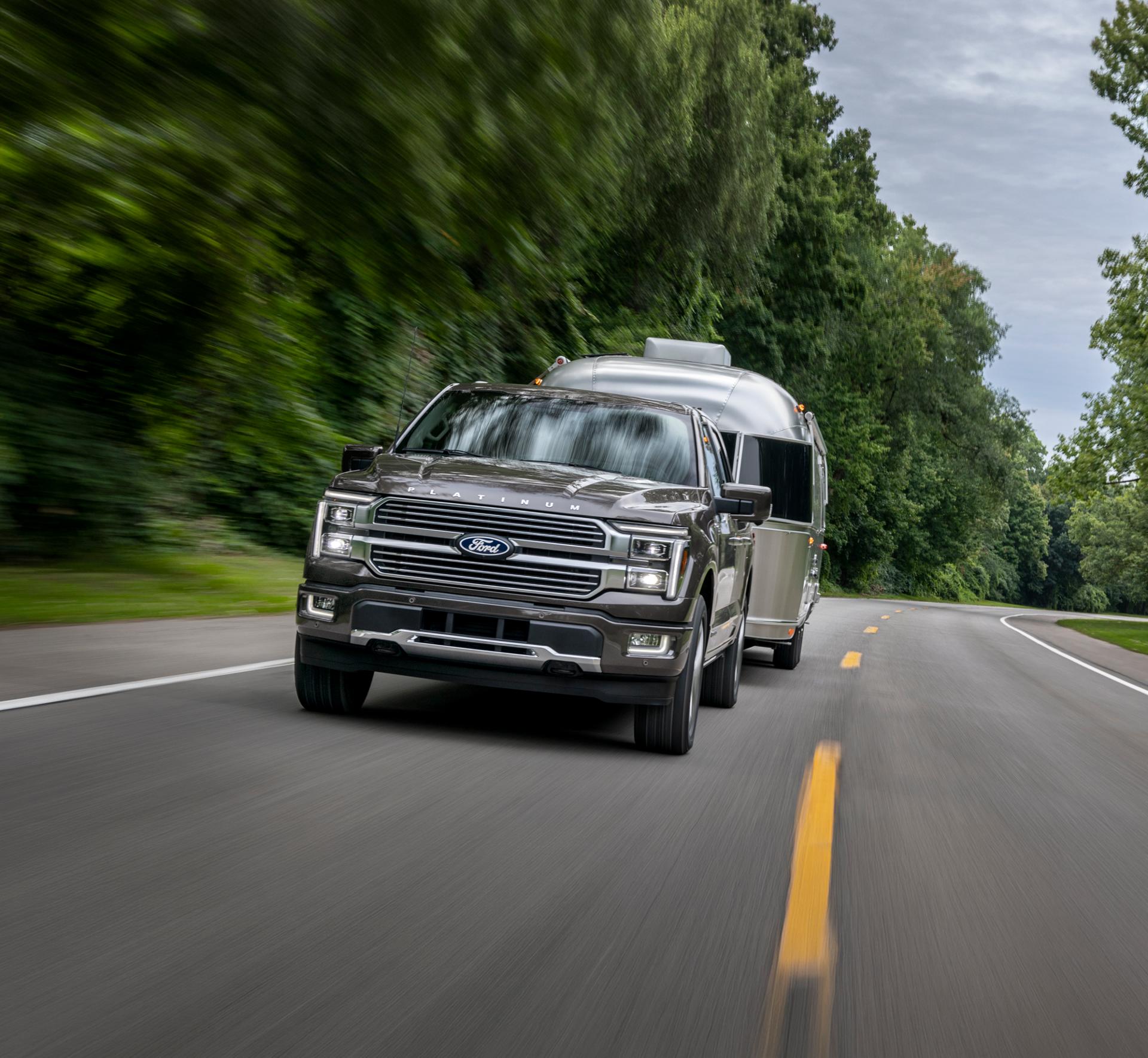A 2025 F-150 with hitched RV trailer driving on a highway.