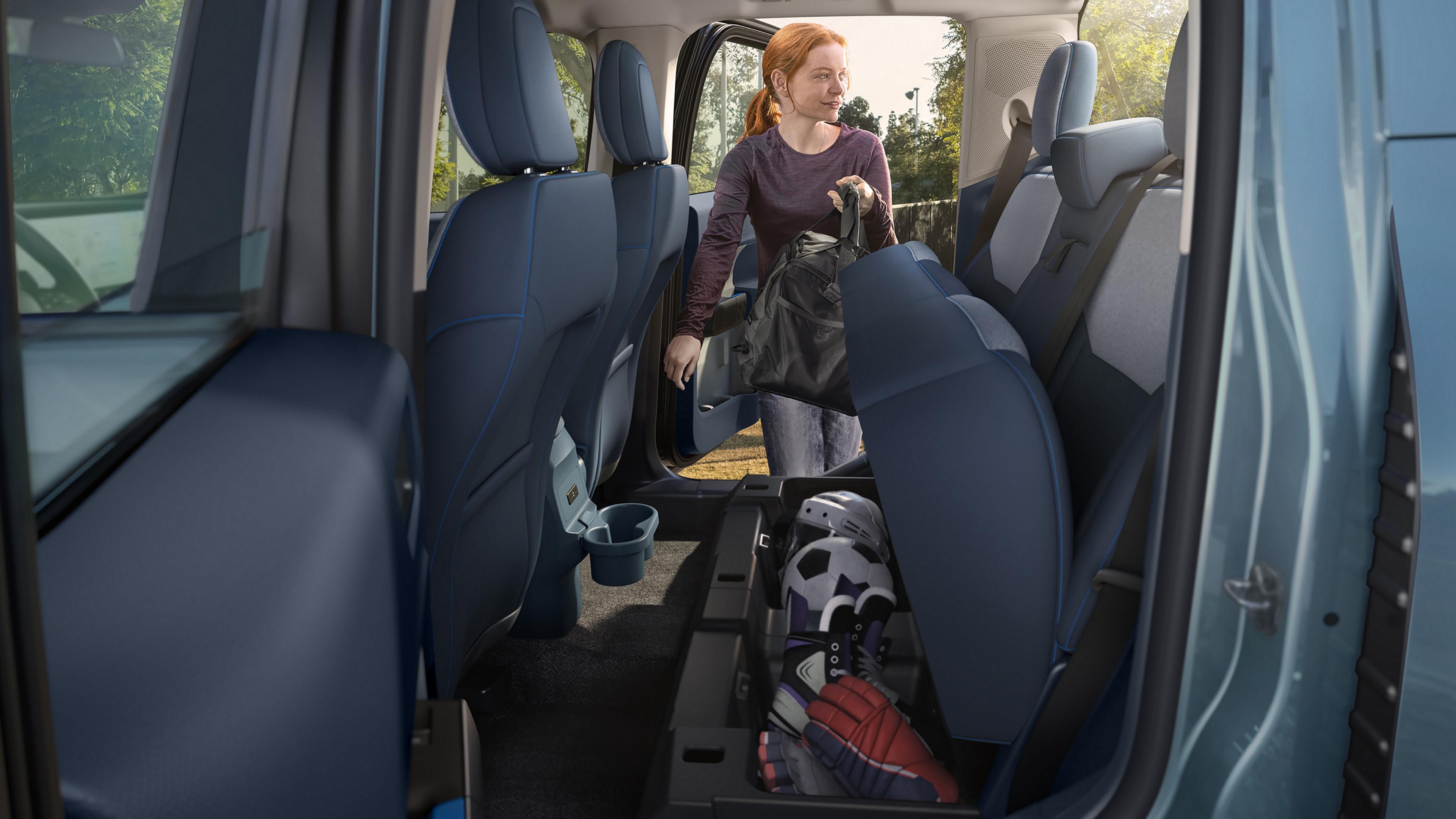 A woman putting a bag into the under-seat storage on a 2026 Ford Maverick® pickup