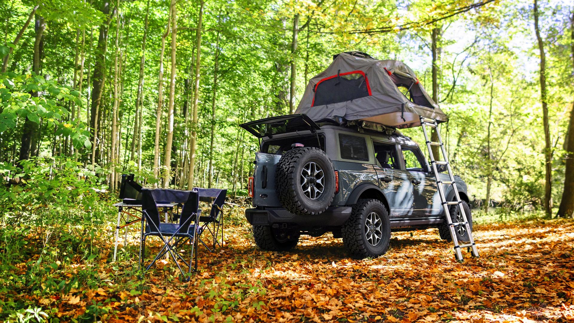 A 2025 Ford Bronco® SUV with a roof tent attached, parked in a forest clearing