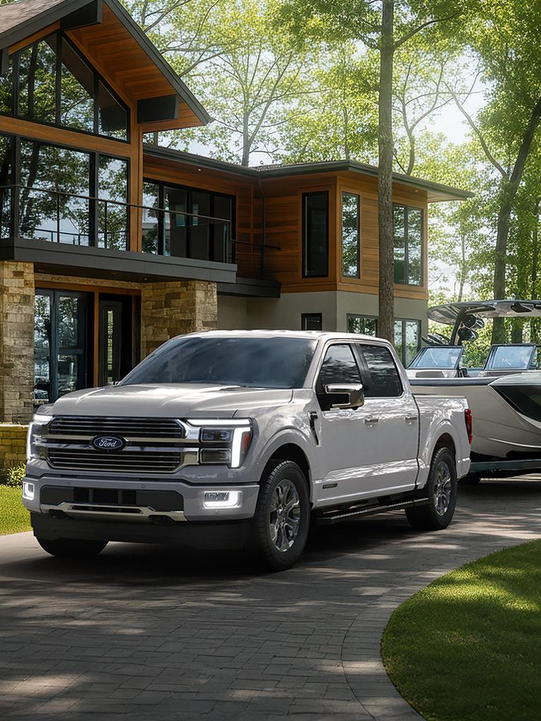 2026 Ford F-150® Platinum® model with Satin Package hitched to a boat trailer parked in front of a house