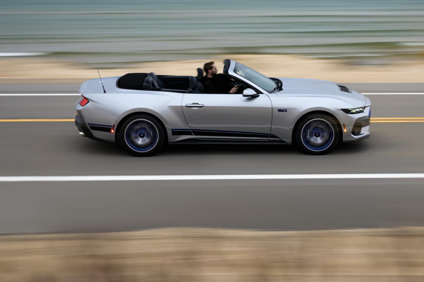 Mustang convertible driving on a highway.
