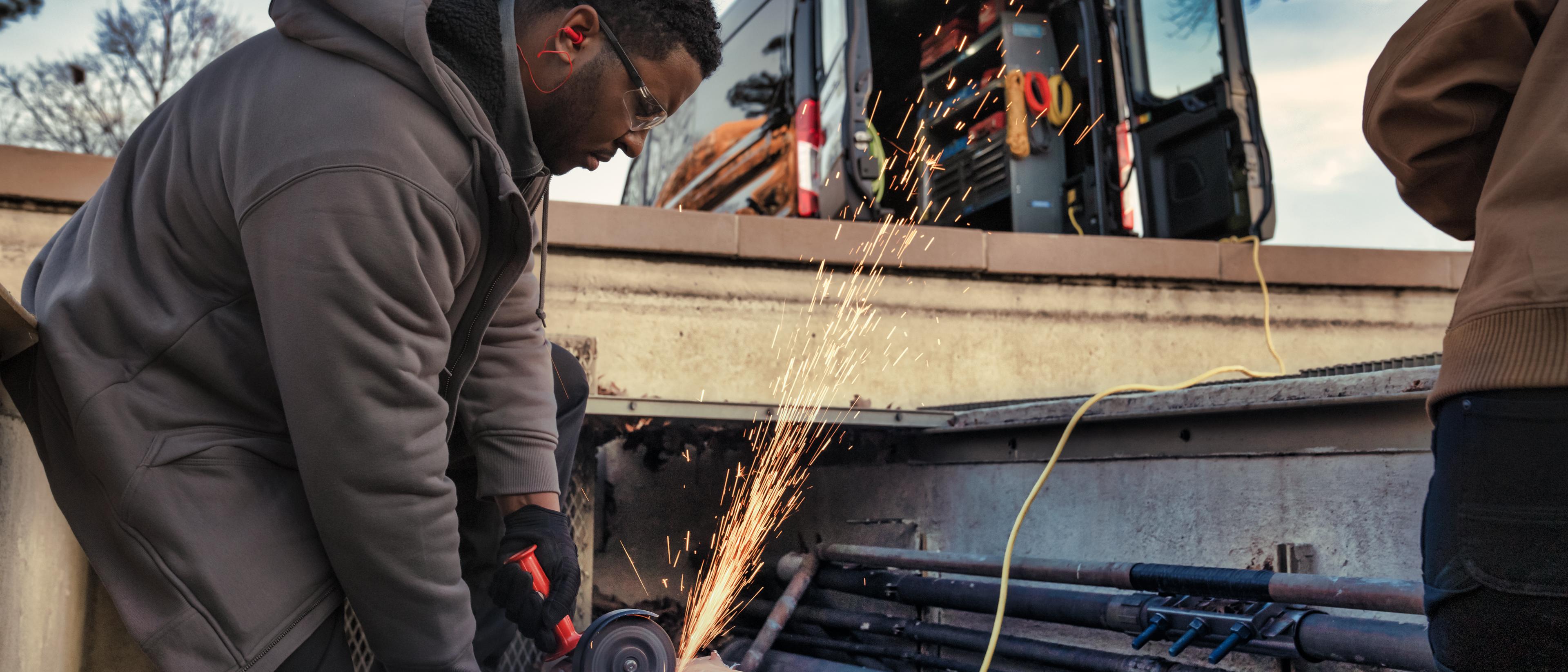 A 2025 Ford E-Transit™ van with rear doors open as workers plug in to Pro Power Onboard™