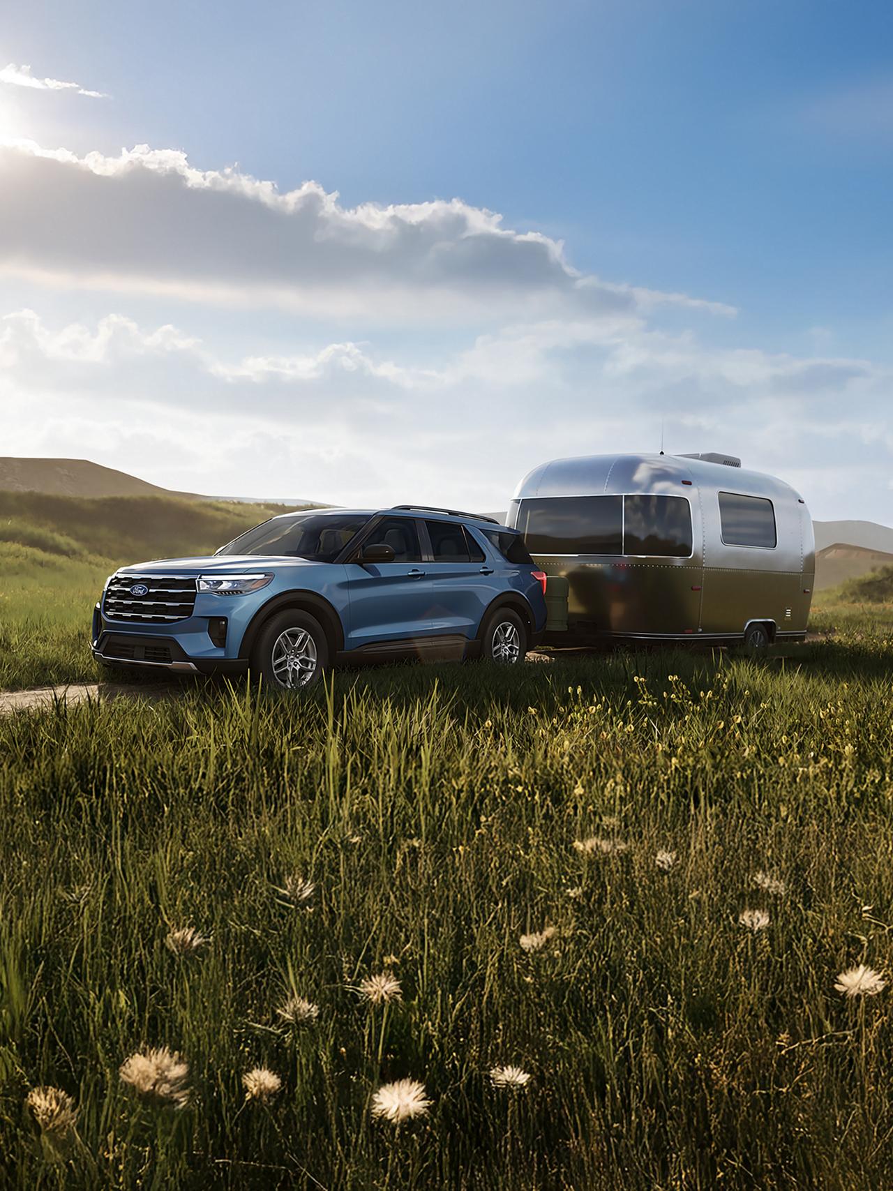 A 2027 Ford Explorer® Active model hitched up to a travel trailer and parked in a field