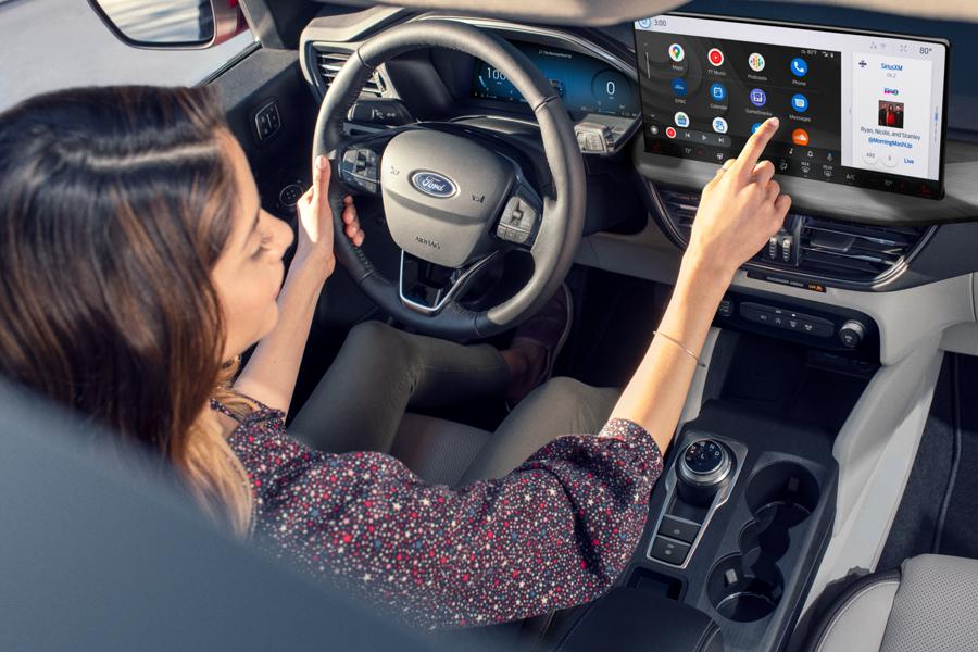 A woman interacts with a touchscreen while driving a Ford vehicle.