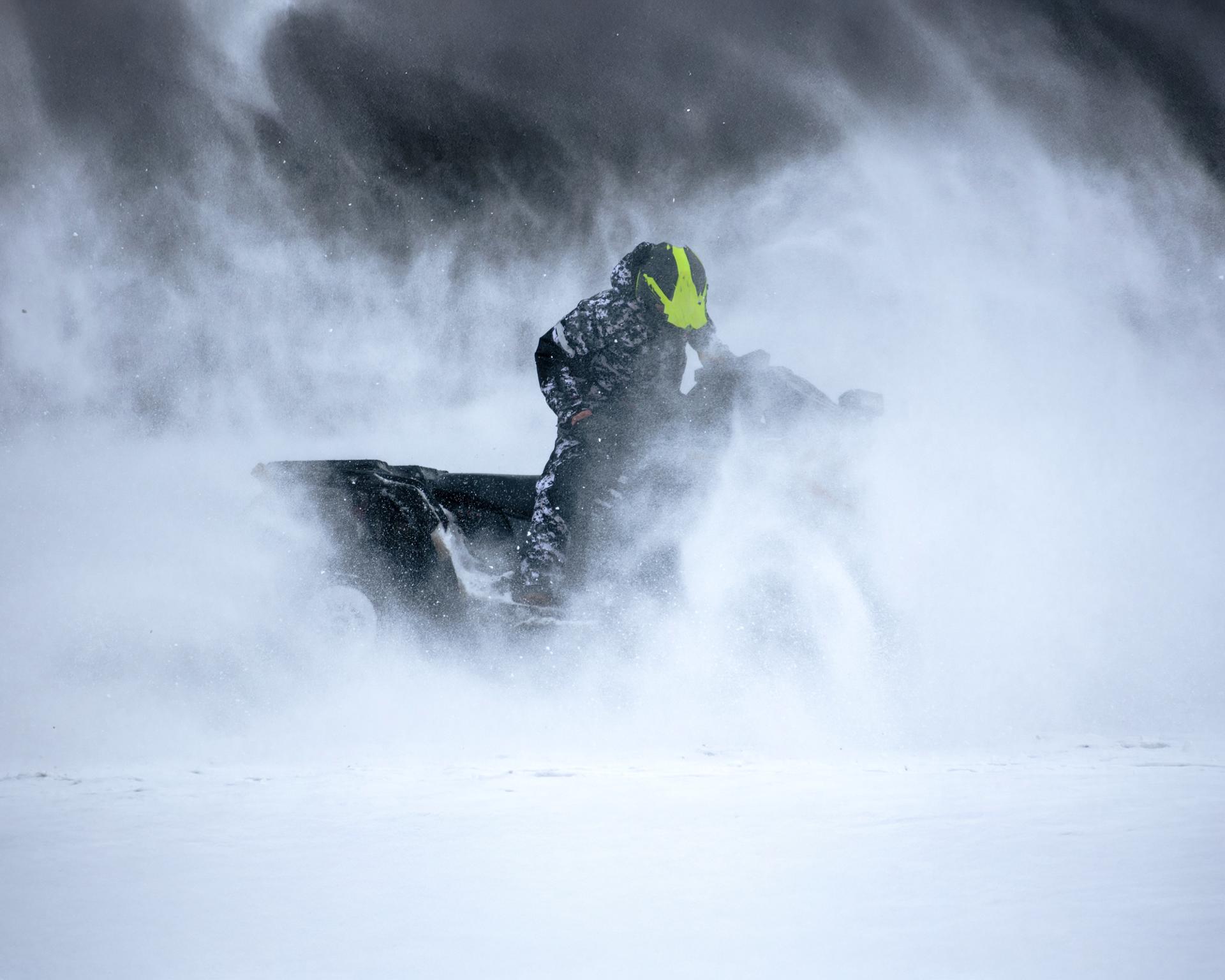 A person operating a snowmobile on a snowy mountain slope.