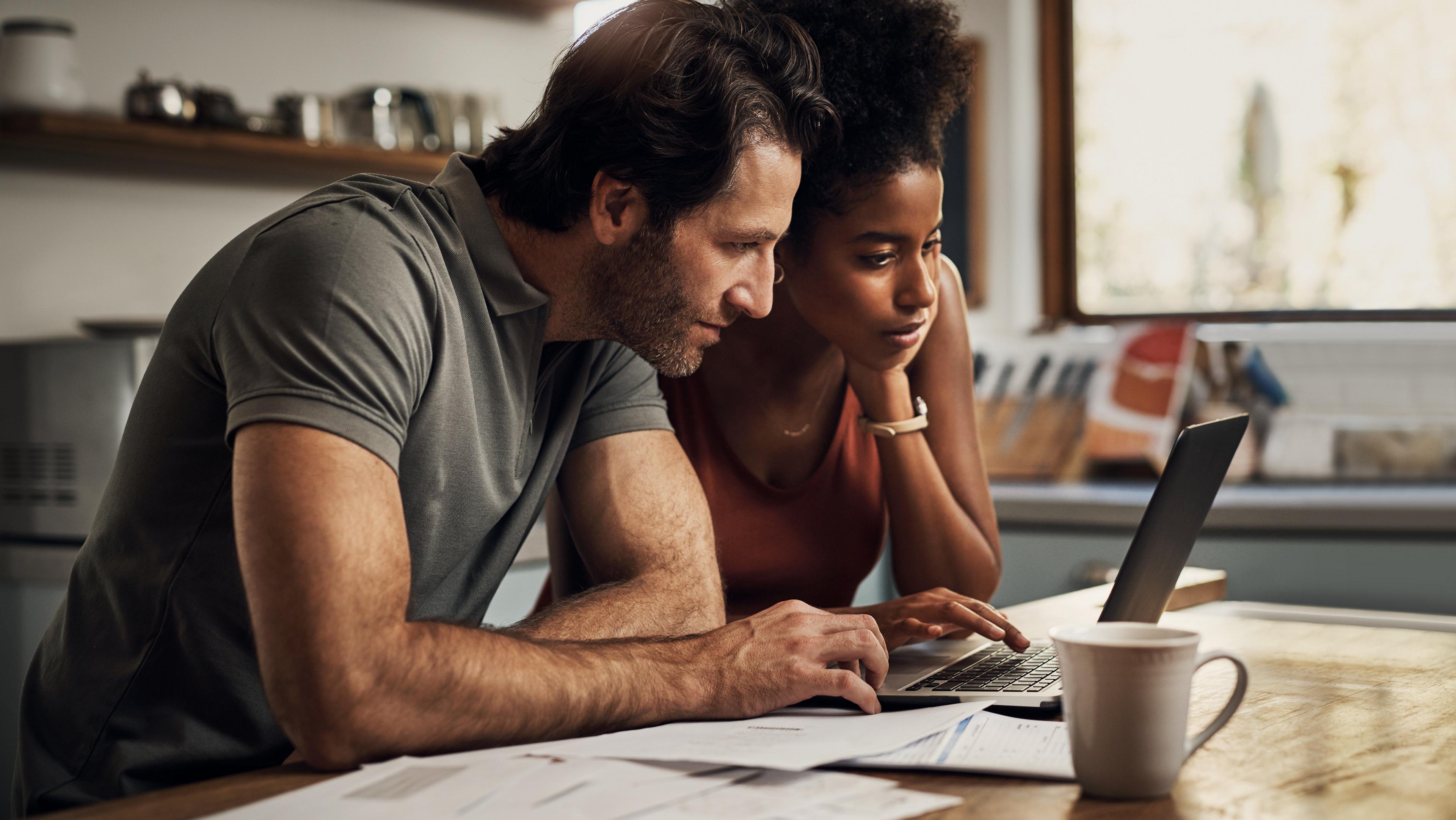 Two people look at a laptop screen.