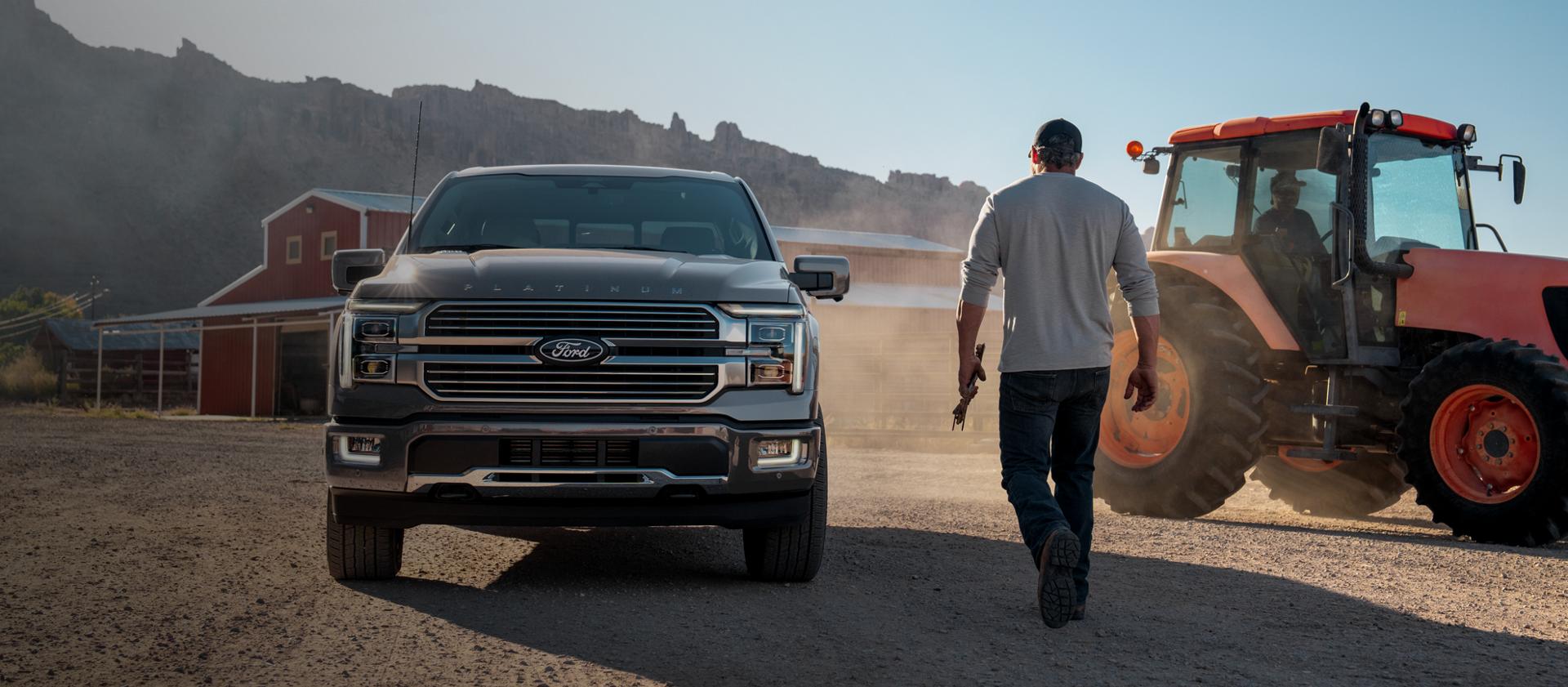 Person walking toward a 2025 Ford F-150 Platinum® pickup parked at a farm