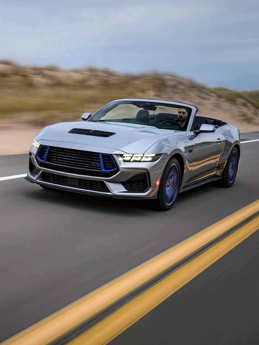 Mustang GT convertible driving on a two-lane highway.
