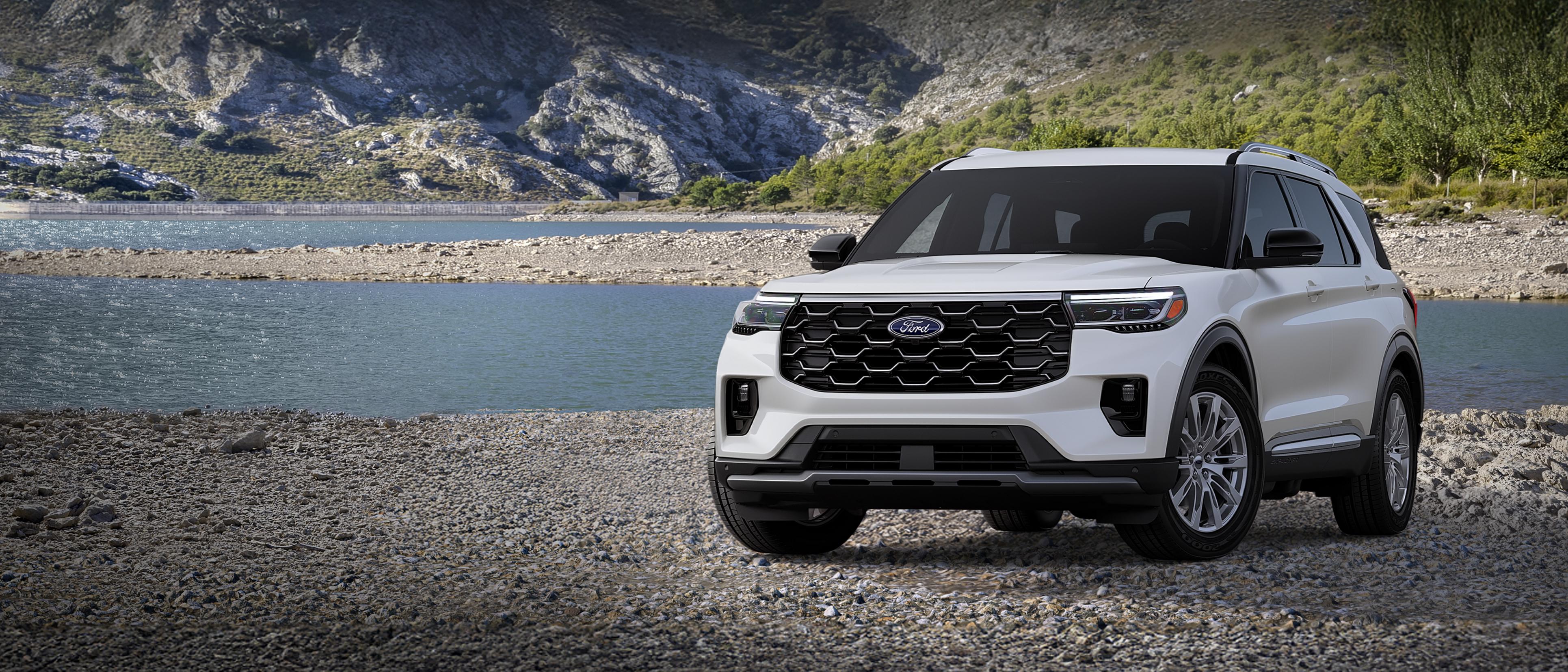 A 2026 Ford Explorer® Platinum™ model parked on a rocky expanse near a mountain lake