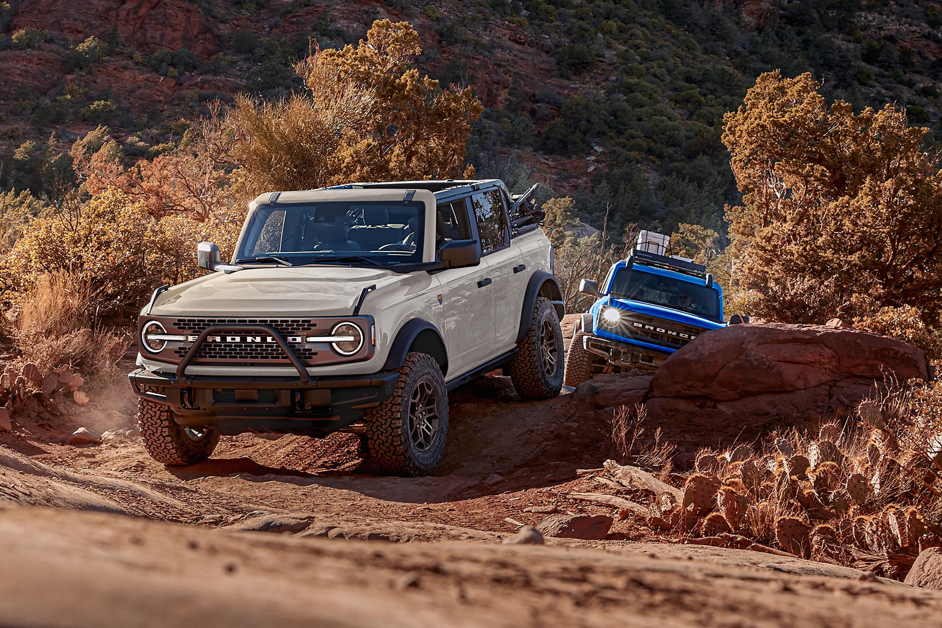 Two 2026 Ford Bronco® SUVs being driven on a scrubby dirt trail