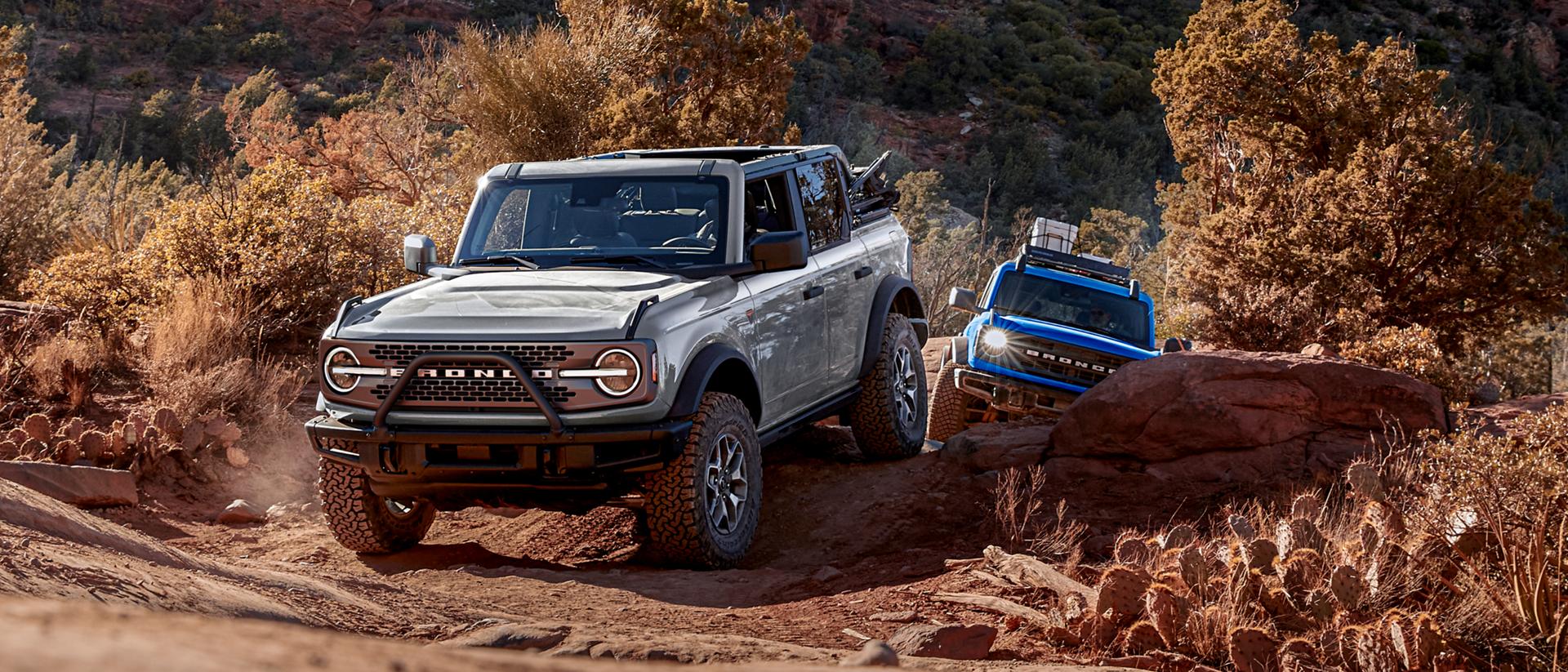 Two 2025 Ford Bronco® SUVs driving on a trail in the high desert