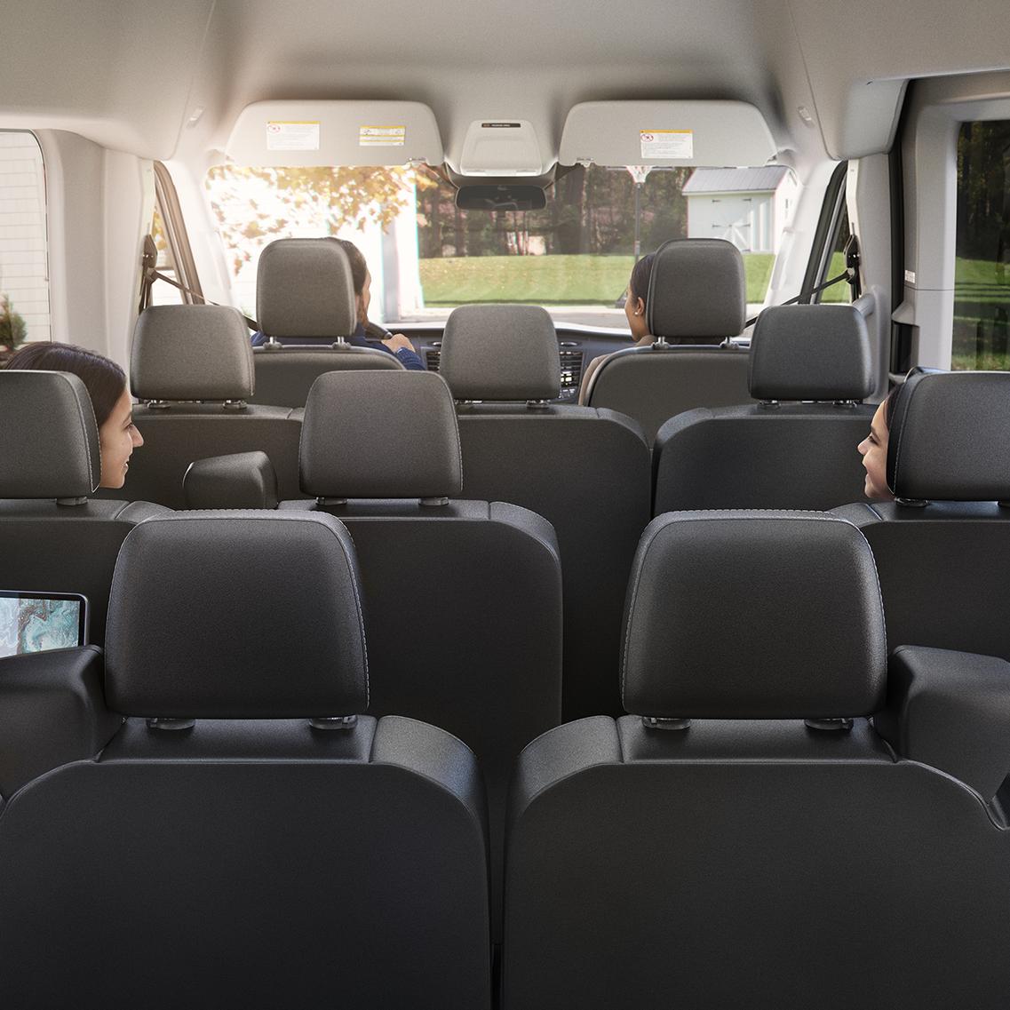 A rear view of the Ford Transit interior with all seats upright and four passengers inside. 
