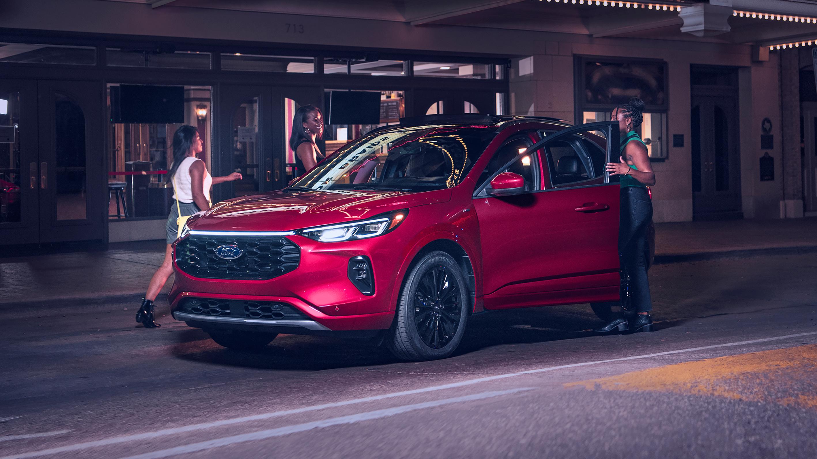 A group of friends get into a red 2025 Ford Escape® SUV at night