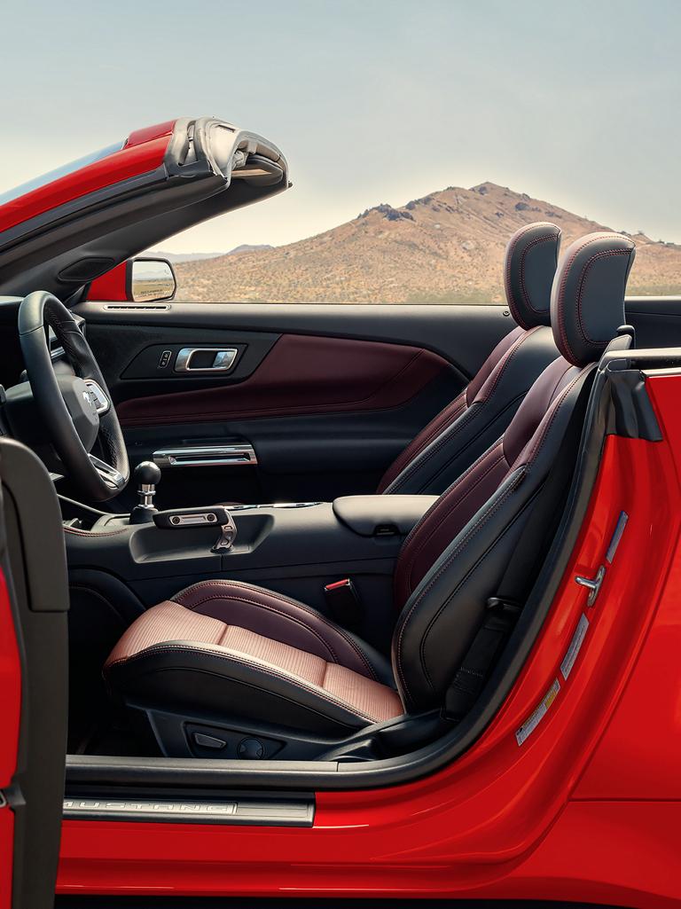 Parked 2026 Ford Mustang® convertible with the driver's side door open showing the available Carmine Red interior