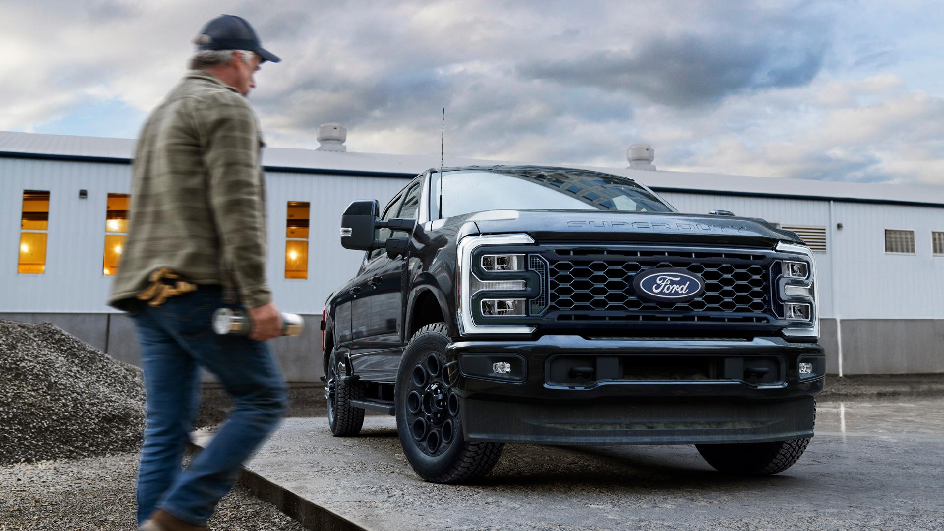 2027 Ford Super Duty® with the Black Appearance Package parked on a cement slab with a person walking toward it