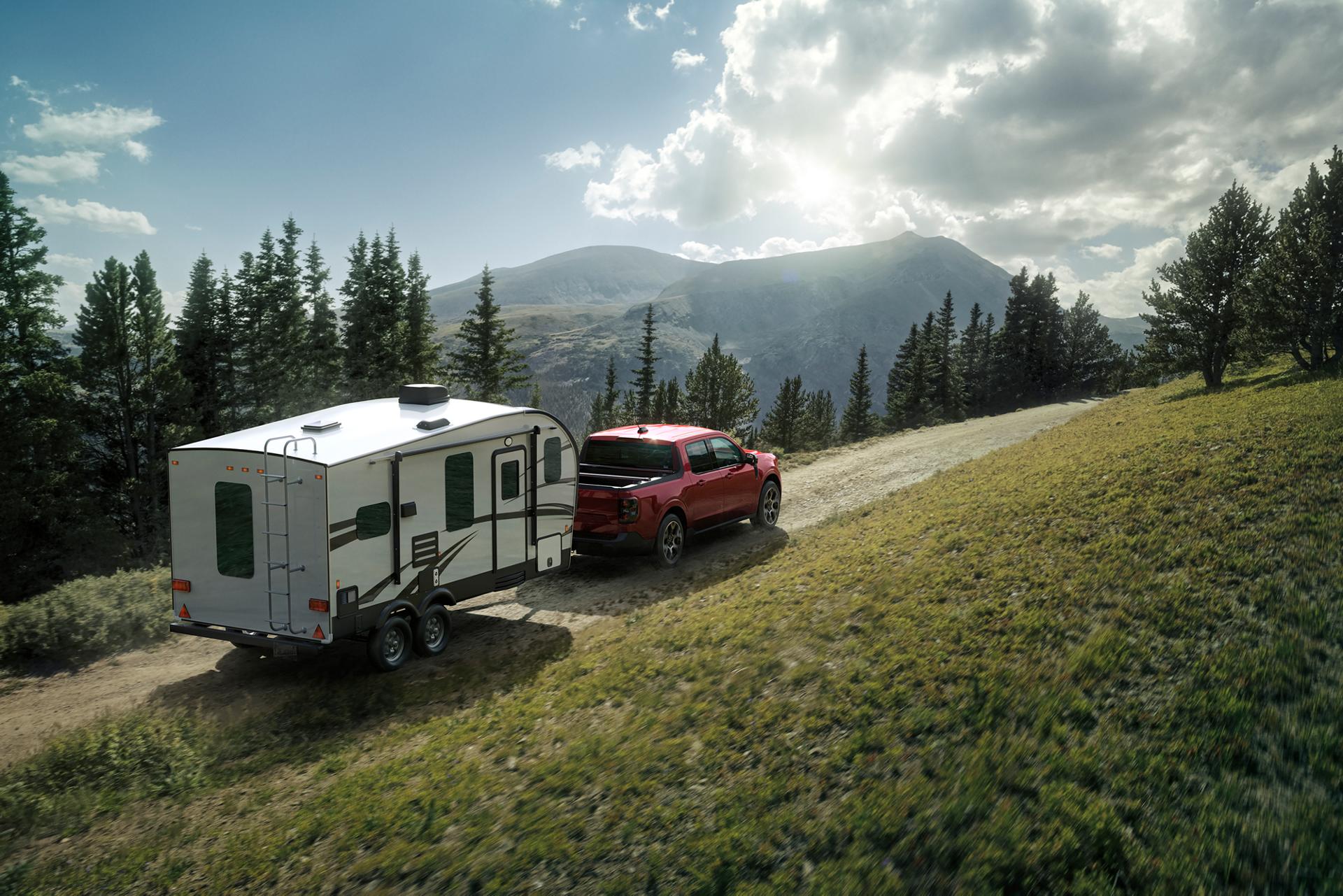 2026 Ford Maverick® Lariat® model in Ruby Red Metallic Tinted Clearcoat (extra cost) pulling a camper on a mountain pass