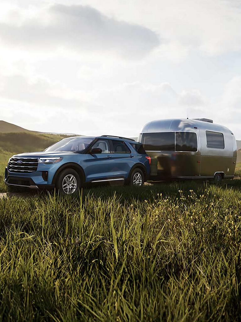 A 2026 Ford Explorer® Active model hitched up to a travel trailer and parked in a field