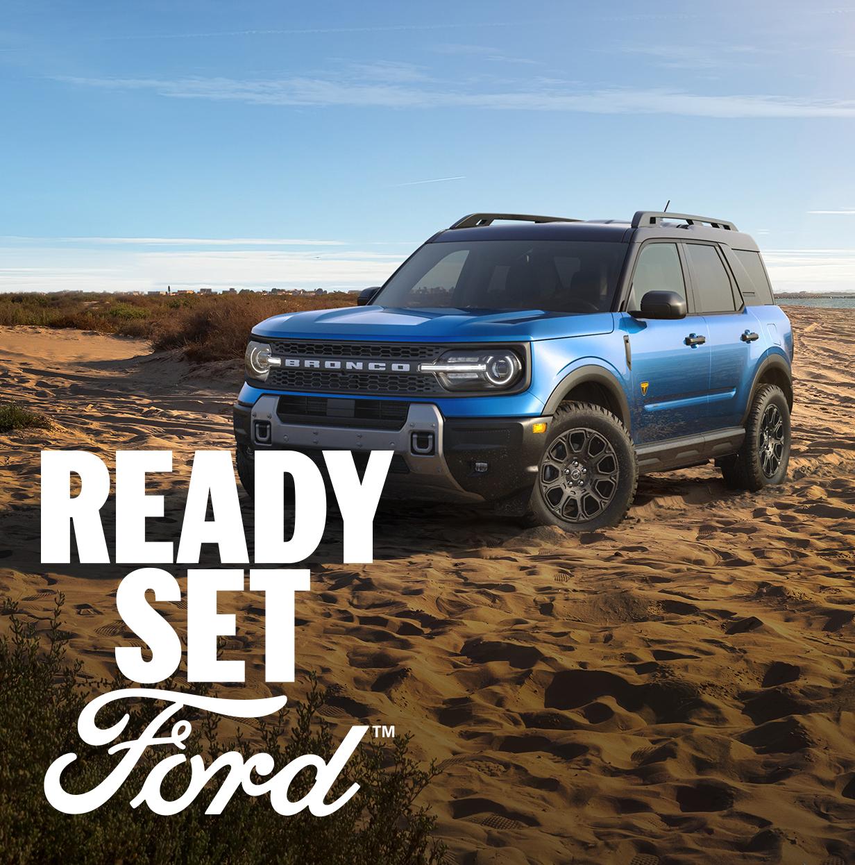 Three-quarter front view of a blue Ford Bronco Sport parked in a desert. White text “Ready Set Ford” appears in the lower left-hand corner. 