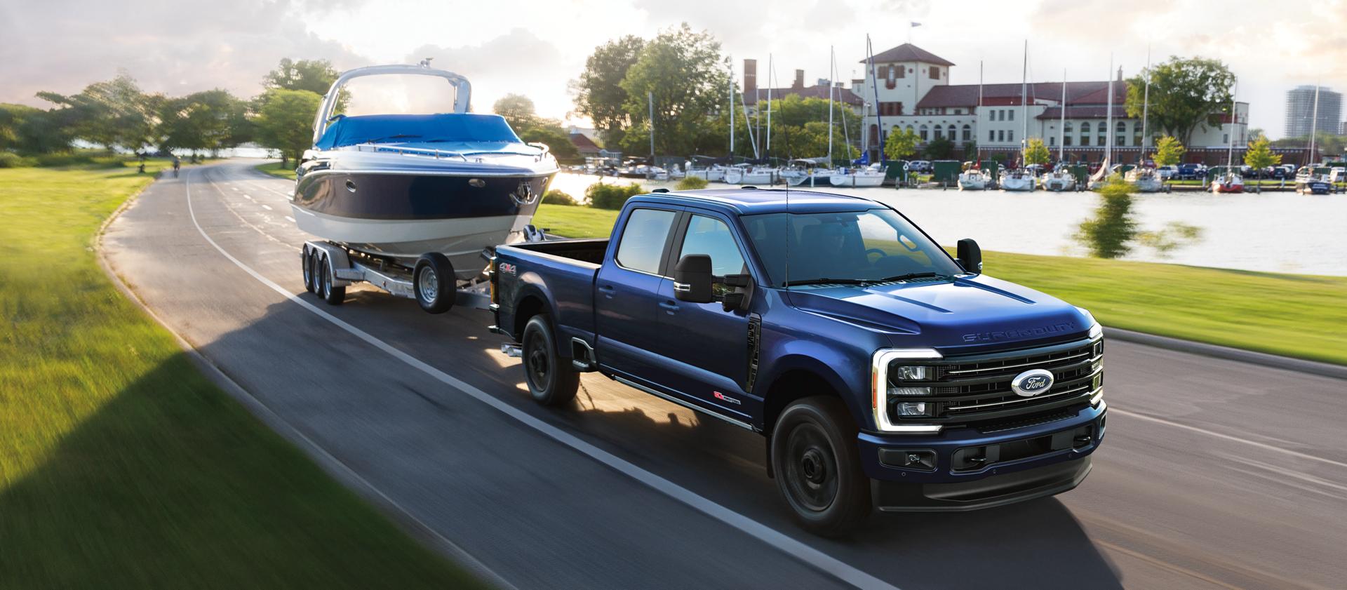 2026 Ford Super Duty® F-350® Platinum® model in Argon Blue towing a speed boat on a paved road
