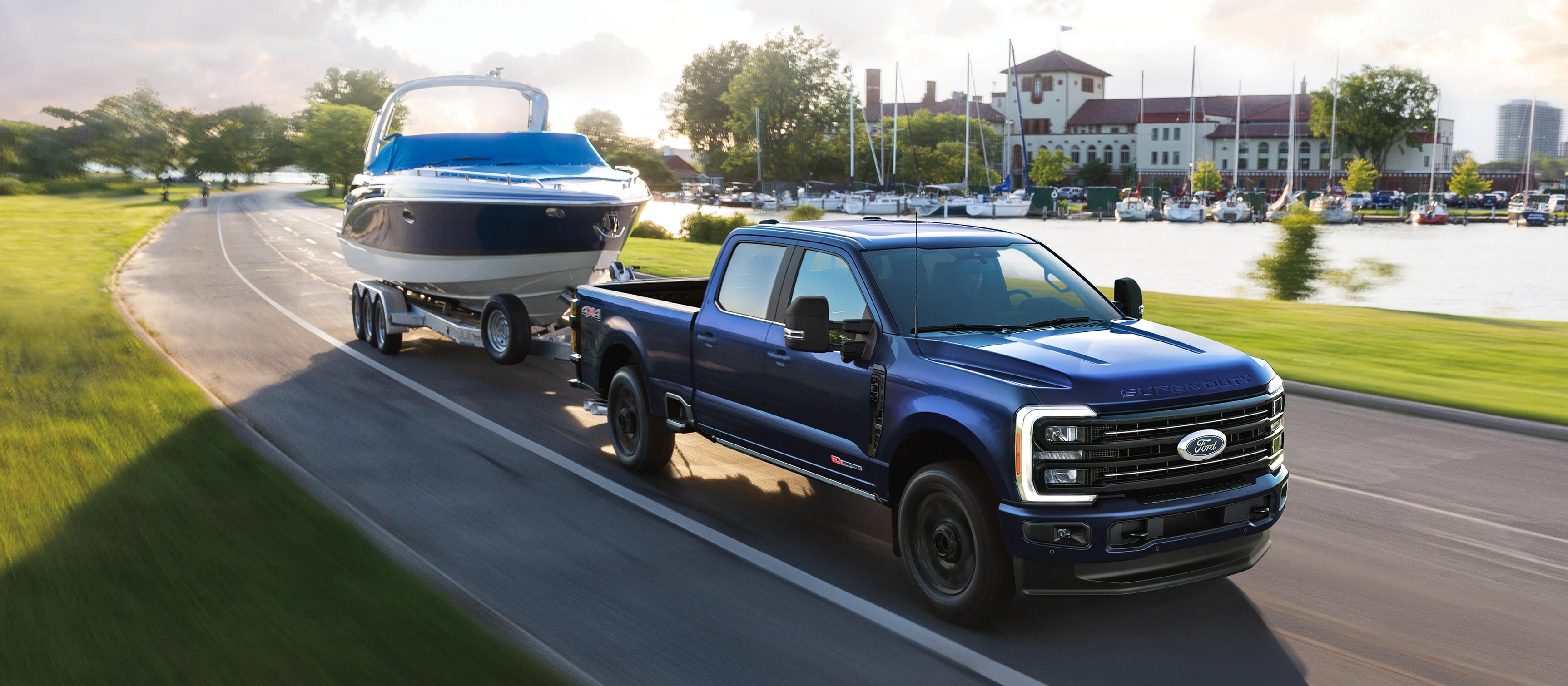 2026 Ford Super Duty® F-350® Platinum® model in Argon Blue towing a speed boat on a paved road