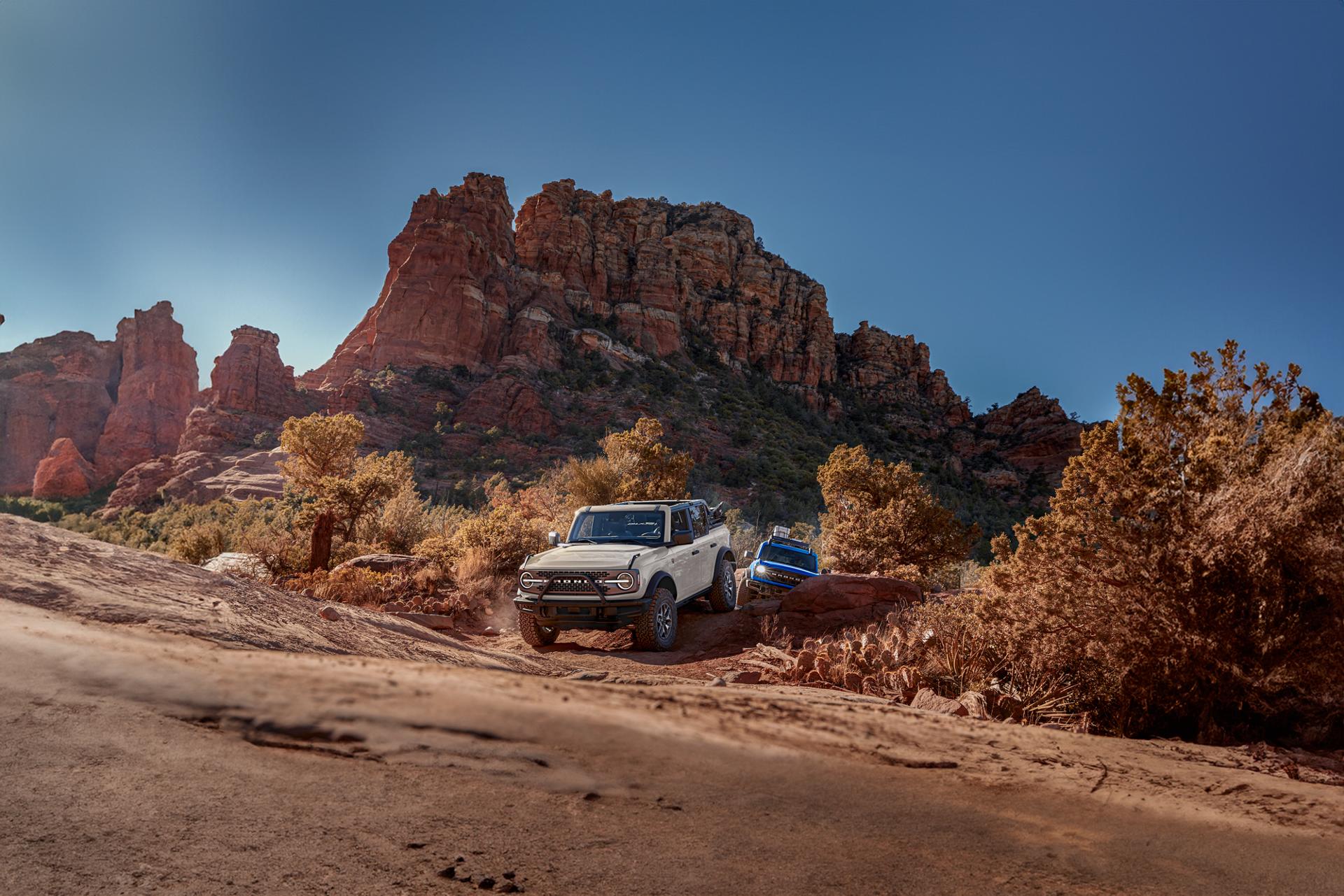 Two Ford Bronco® SUVs crawl up boulders and rugged terrain.