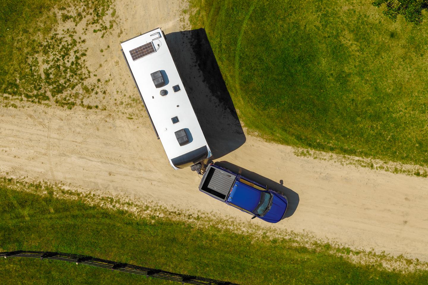 Aerial view of an F-150 driving on a dirt road and hauling a trailer.
