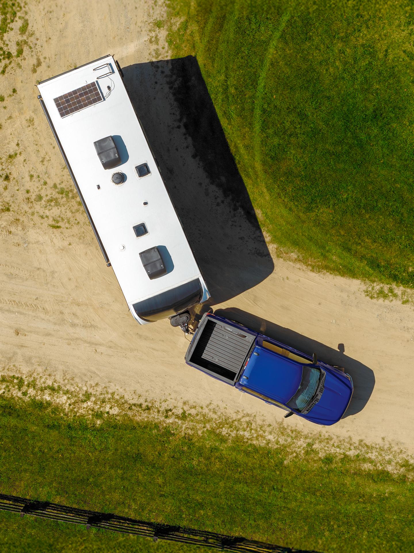 Aerial view of an F-150 driving on a dirt road and hauling a trailer.