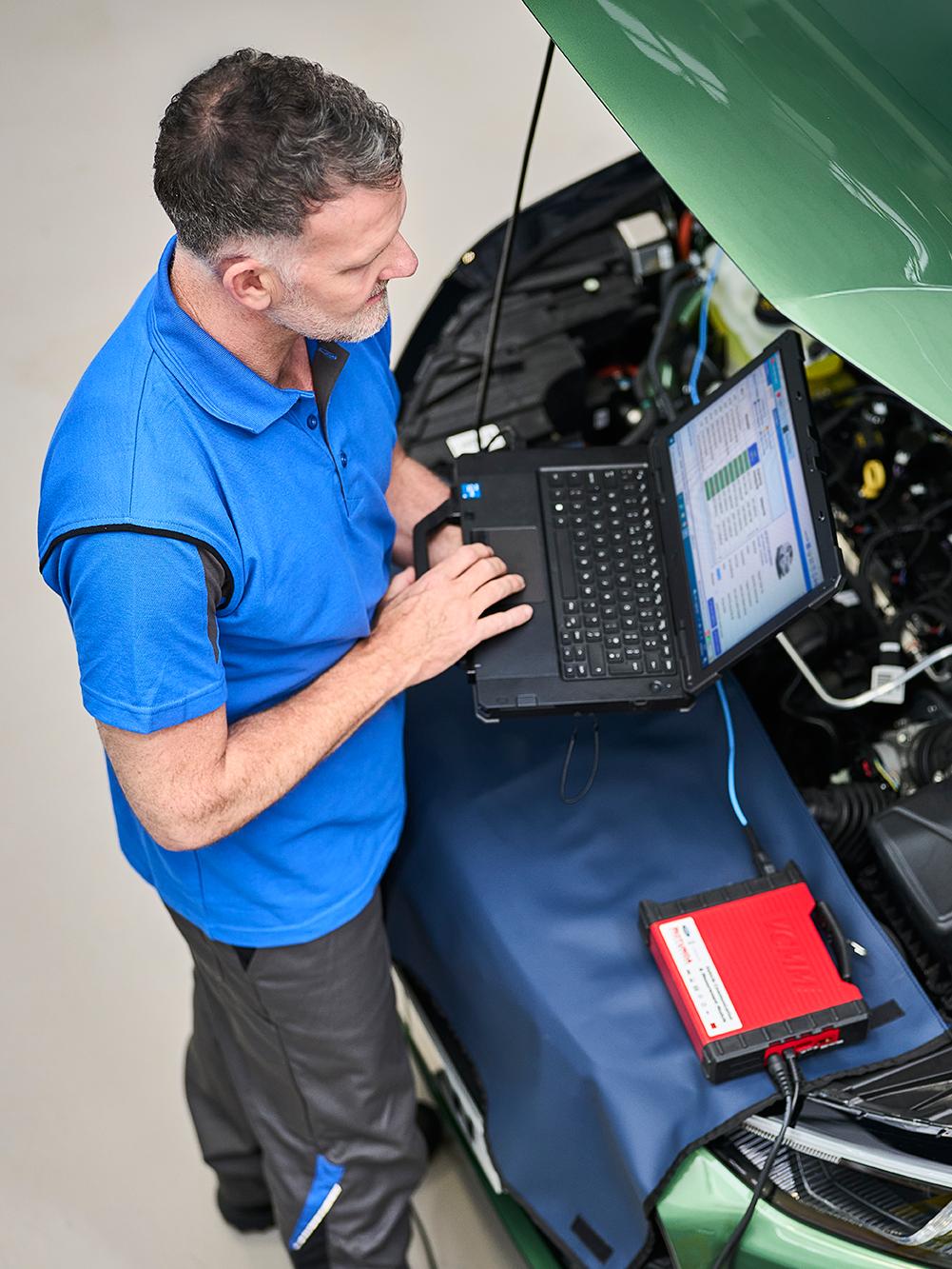 A service technician checks a Ford vehicle with a laptop.