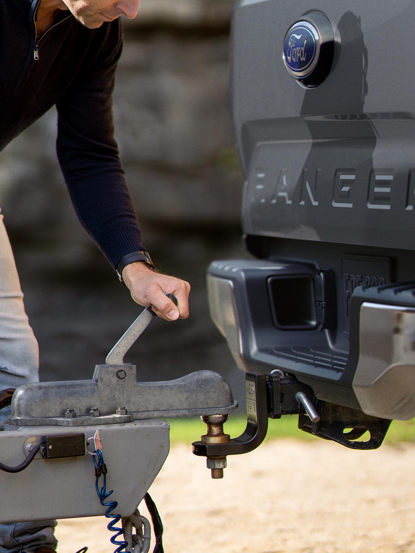 A person's hand is using the available Trailer Tow Package to hitch a trailer to their 2026 Ford Ranger® XL truck