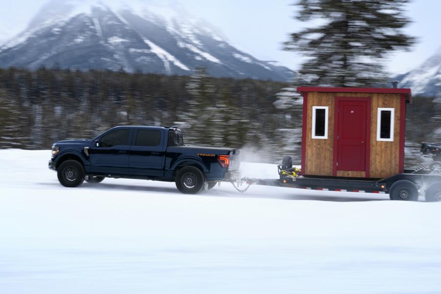 F-150 Tremor hauling an ice fishing hut and ATV on an icy mountain road.