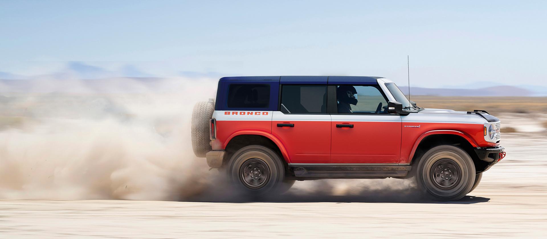 A 2026 Ford Bronco® Stroppe Edition SUV kicking up sand on a salt pan in the desert