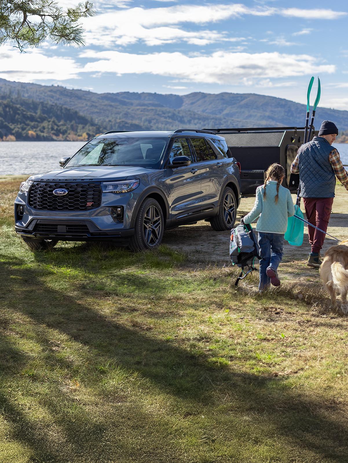 A grey Ford Explorer® parked by a lake with a trailer attached to the trunk.