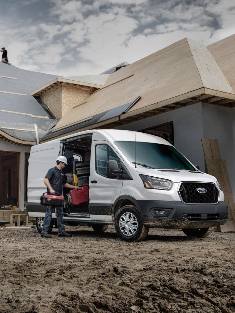 A white 2027 Ford Transit® work van parked at a residential construction site with workers