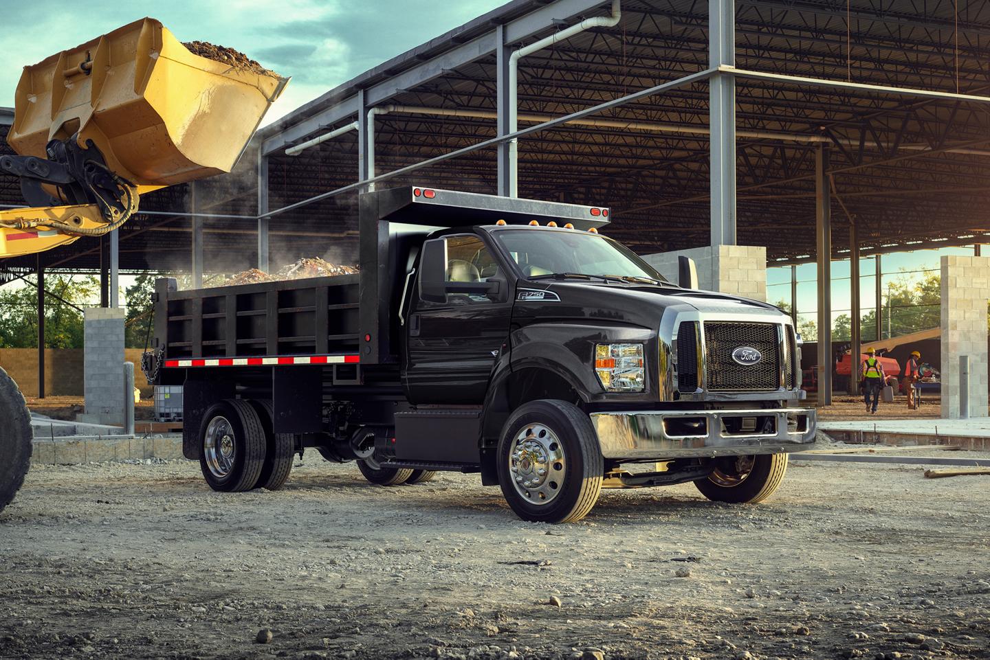 A black Ford Medium Duty truck with dump truck upfit parked in front of a construction site