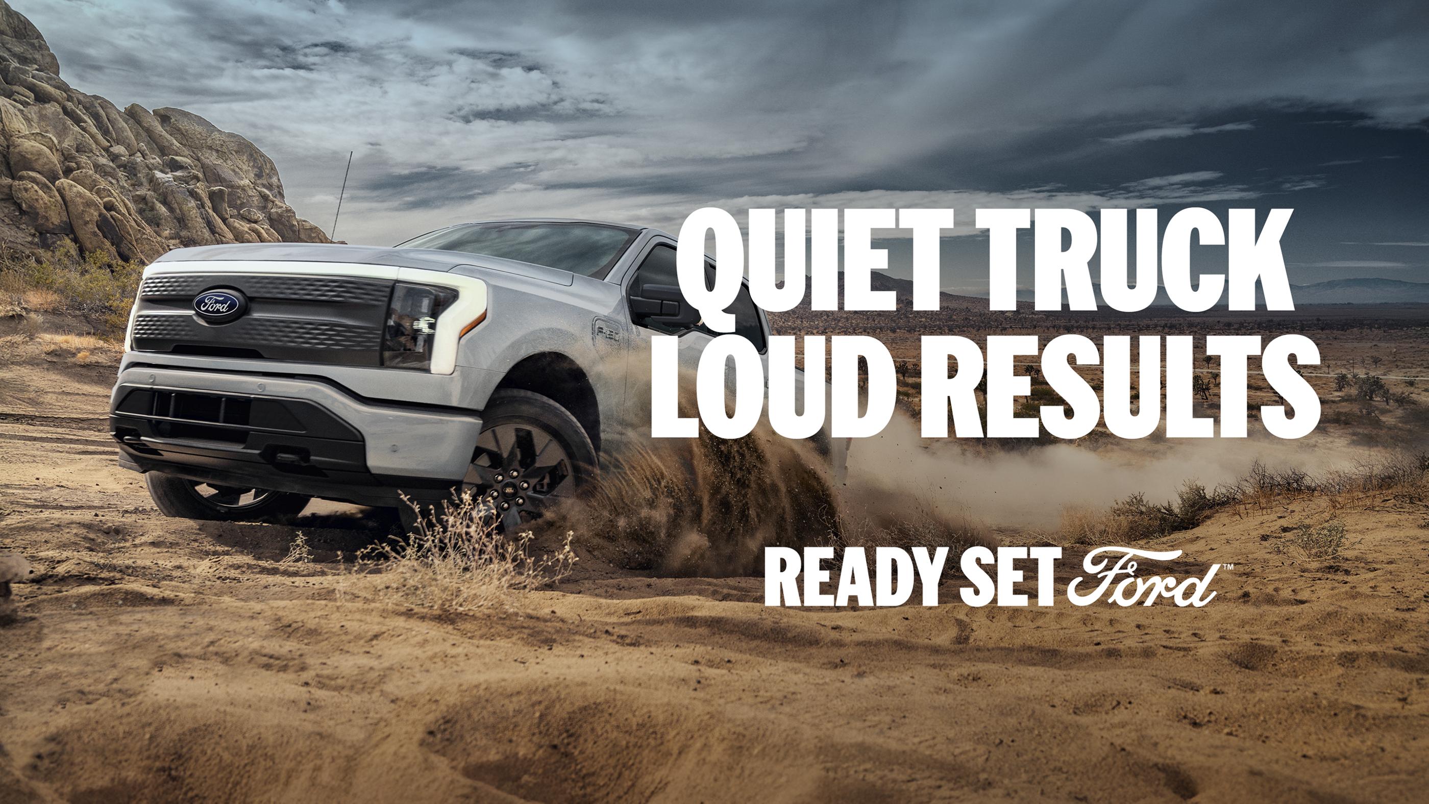 Three-quarter aerial profile of a white Ford F-150 Lightning off-roading across open terrain. 