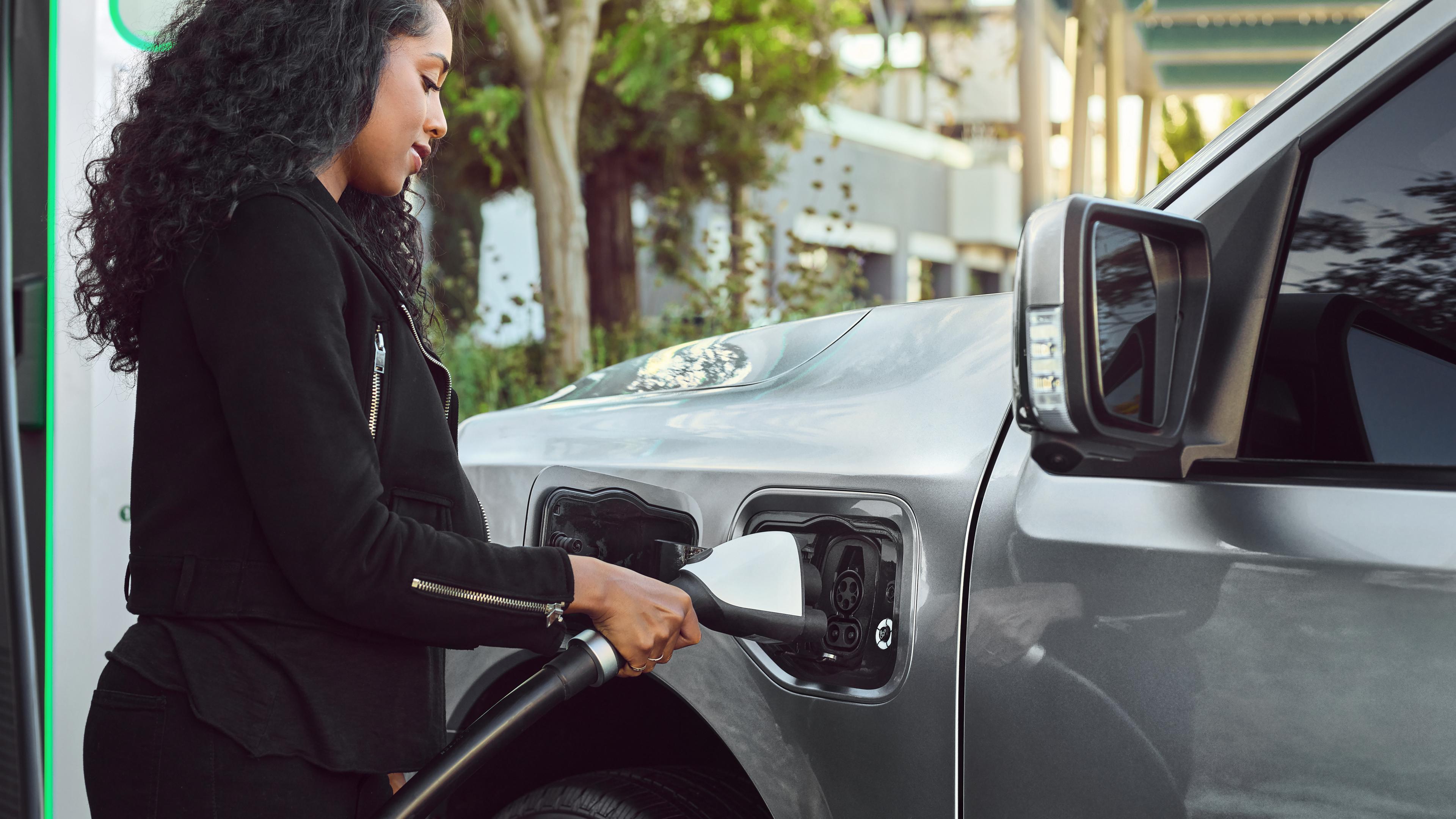 A woman plugging a charger into the charge port on a 2025 Ford F-150® Lightning® pickup