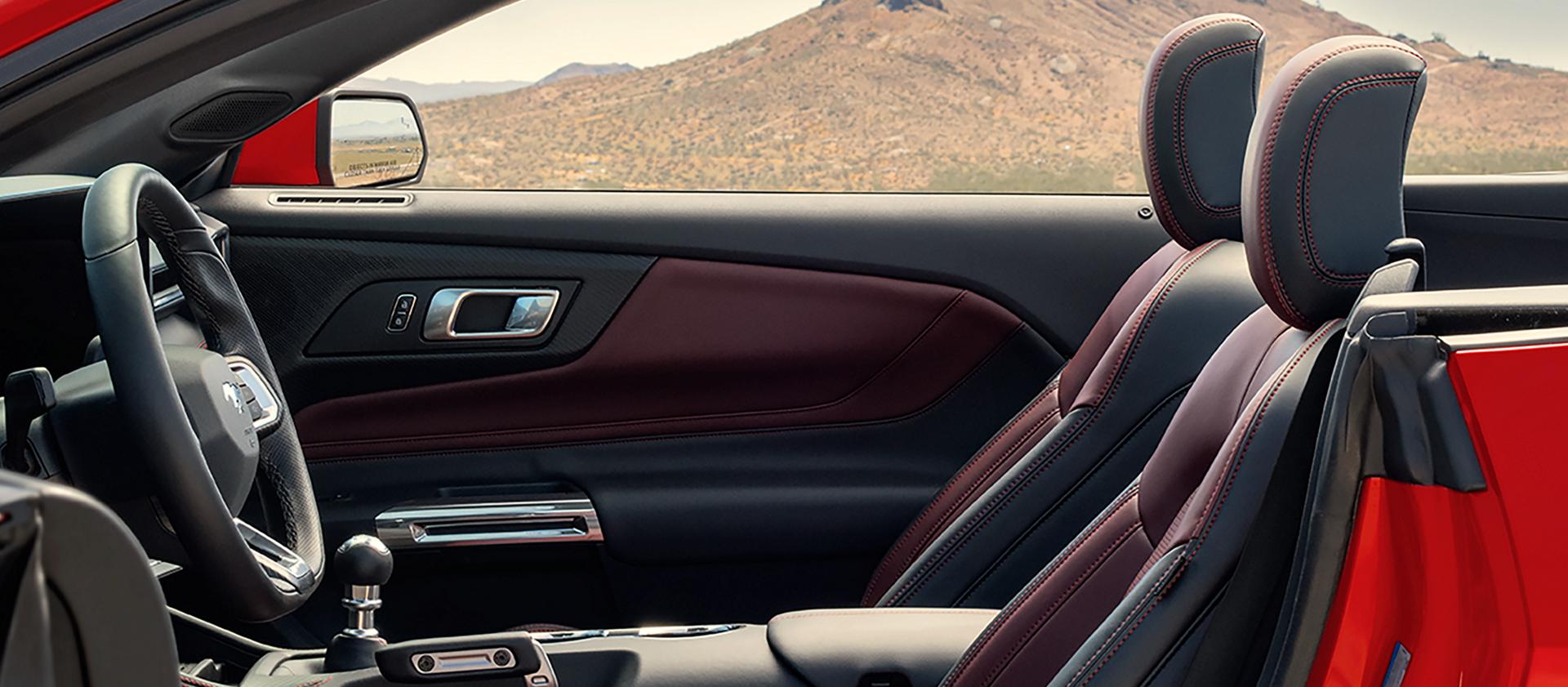 Parked 2026 Ford Mustang® convertible with the driver's side door open showing the available Carmine Red interior