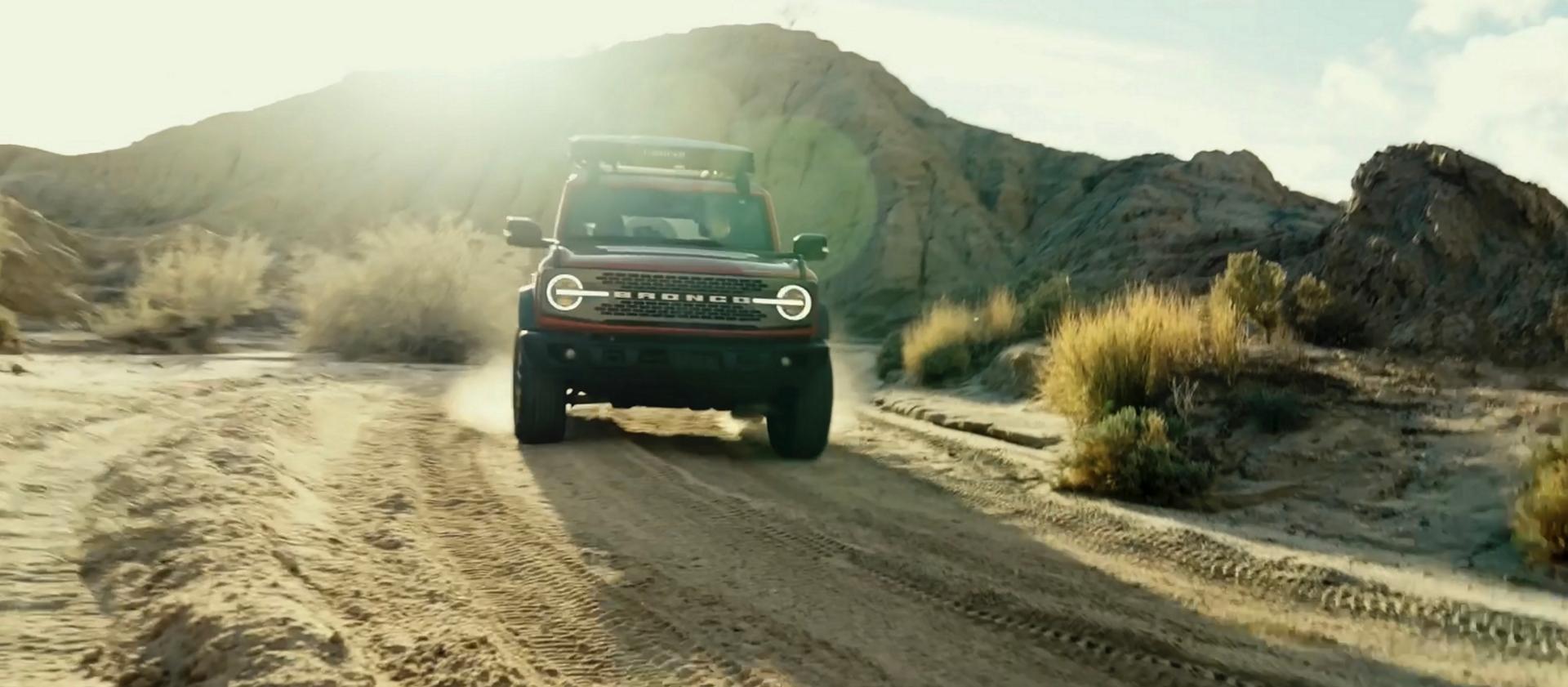 A 2026 Ford Bronco® SUV being driven on a dirt trail through a stark, dusty landscape